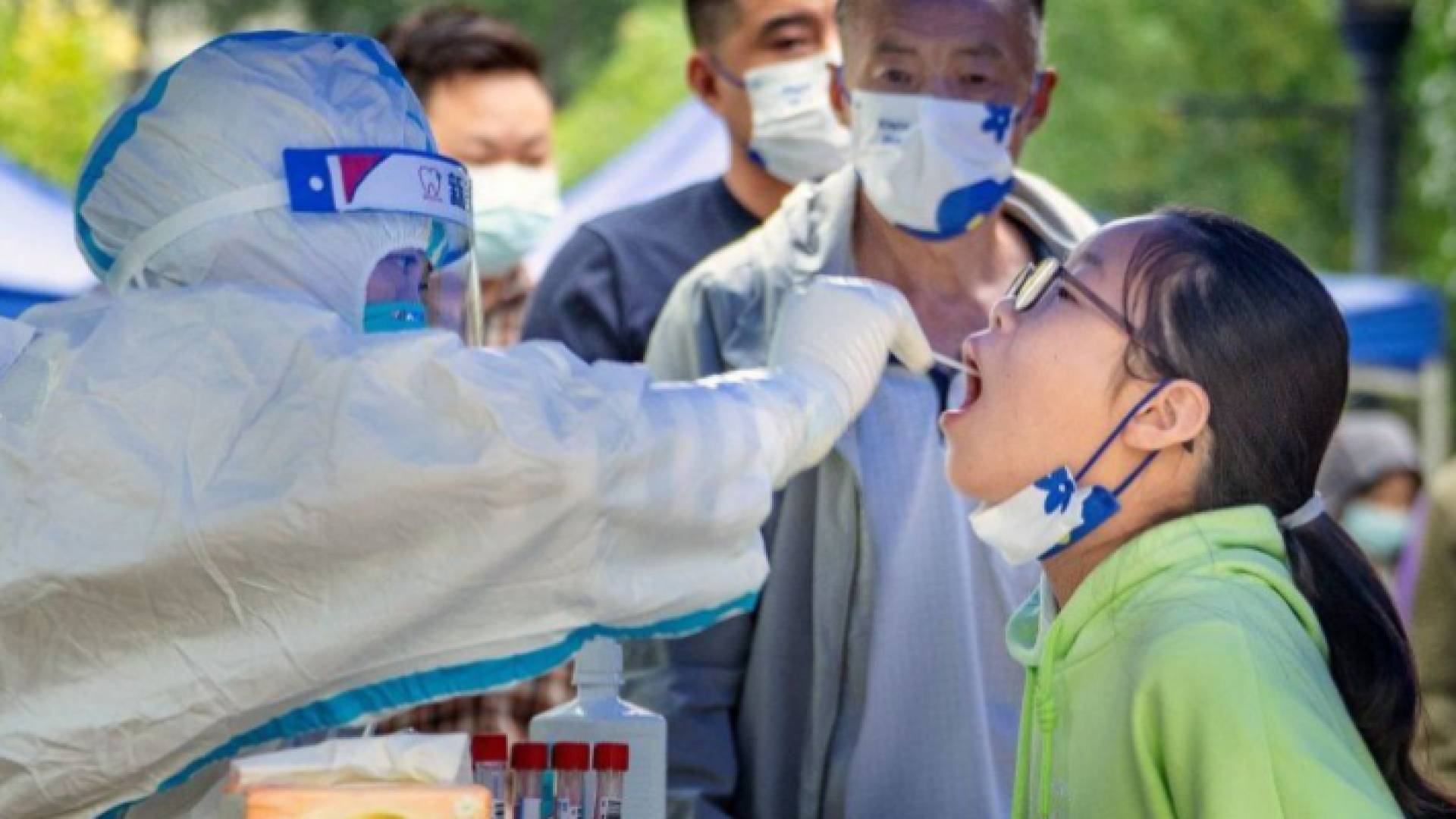 عامل في القطاع الصحي الصيني يأخذ عينة من طفلة للتحقق من إصابتها بكورونا