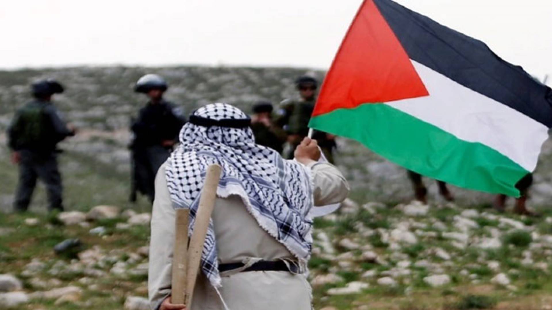 مسن يحمل علم فلسطين أمام جنود الاحتلال