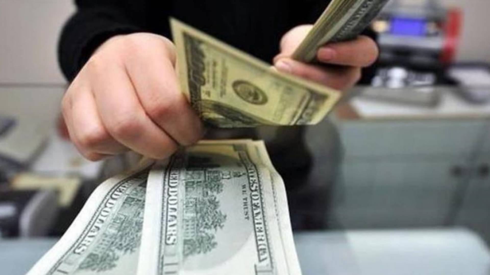 شخص بيده مبالغ نقدية بعملة الدولار
