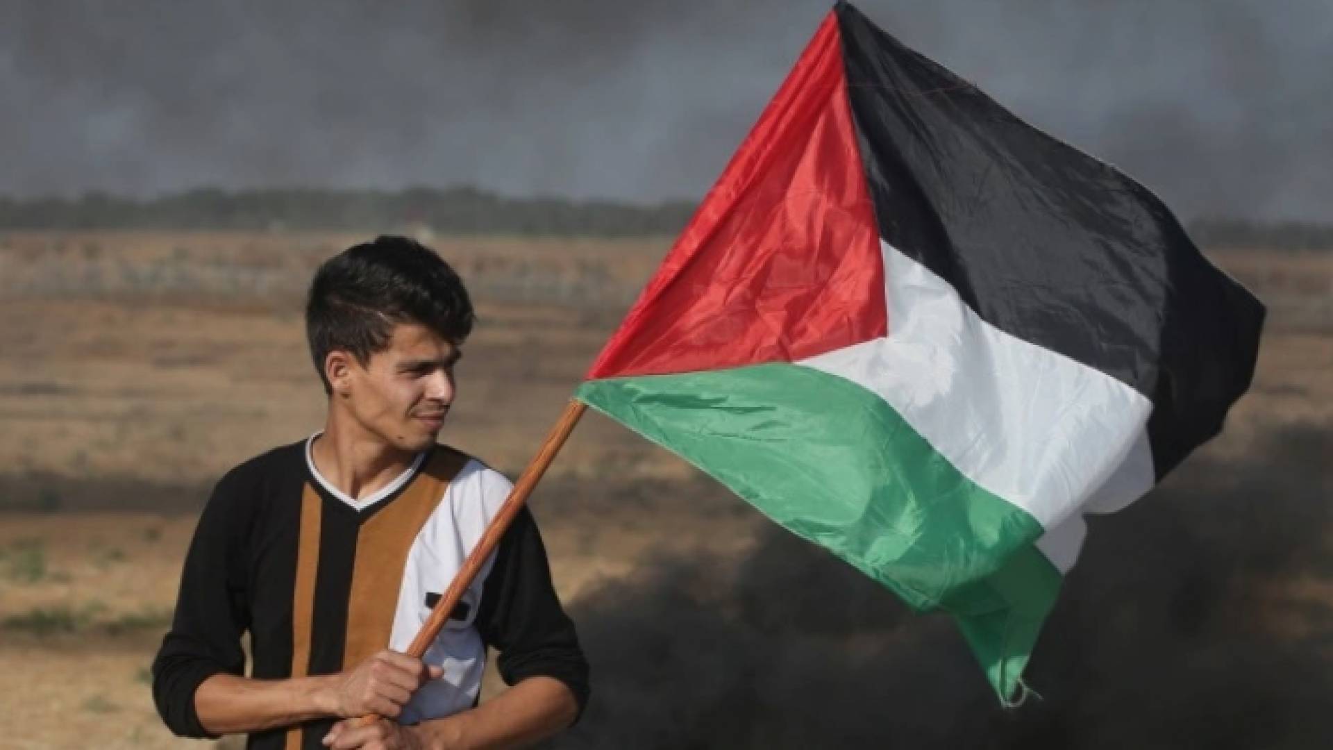 شاب فلسطيني يرفع العلم الفلسطيني