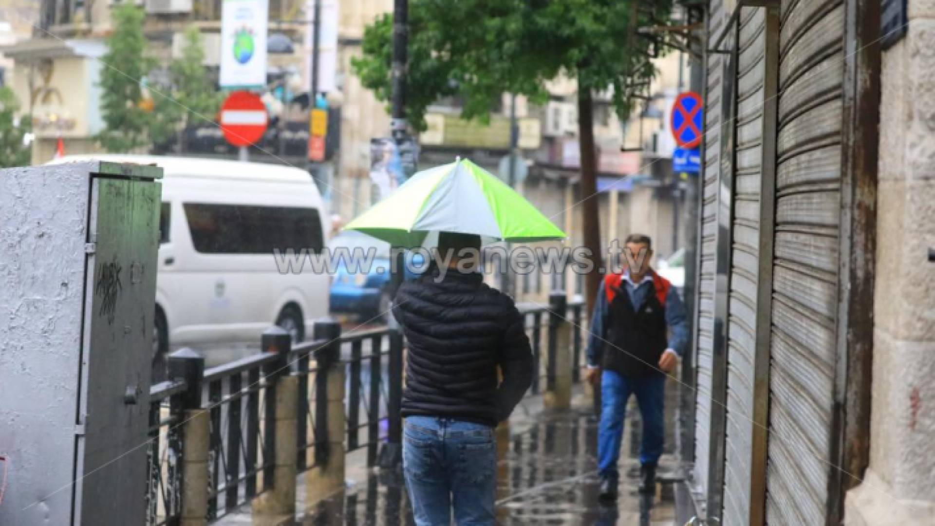 شخص يحمل مظلة تحت المطر في وسط البلد بالعاصمة عمان