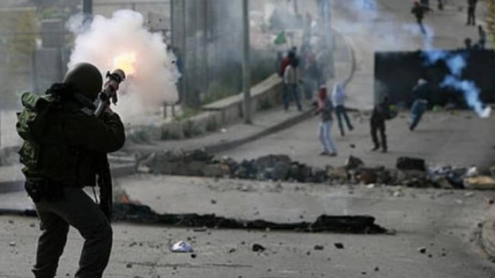 جندي من قوات الاحتلال يصوب بندقيته نحو فلسطينيين
