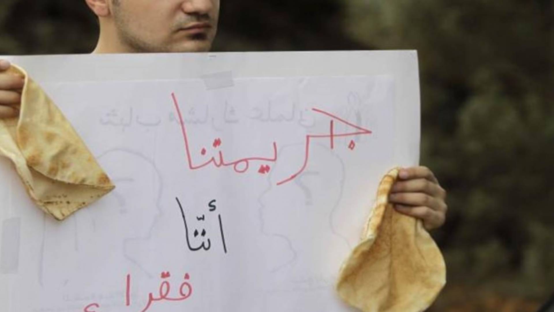 صورة تعبيرية لمواطن يرفع فيها لافتة توحي بمعاناته من الفقر