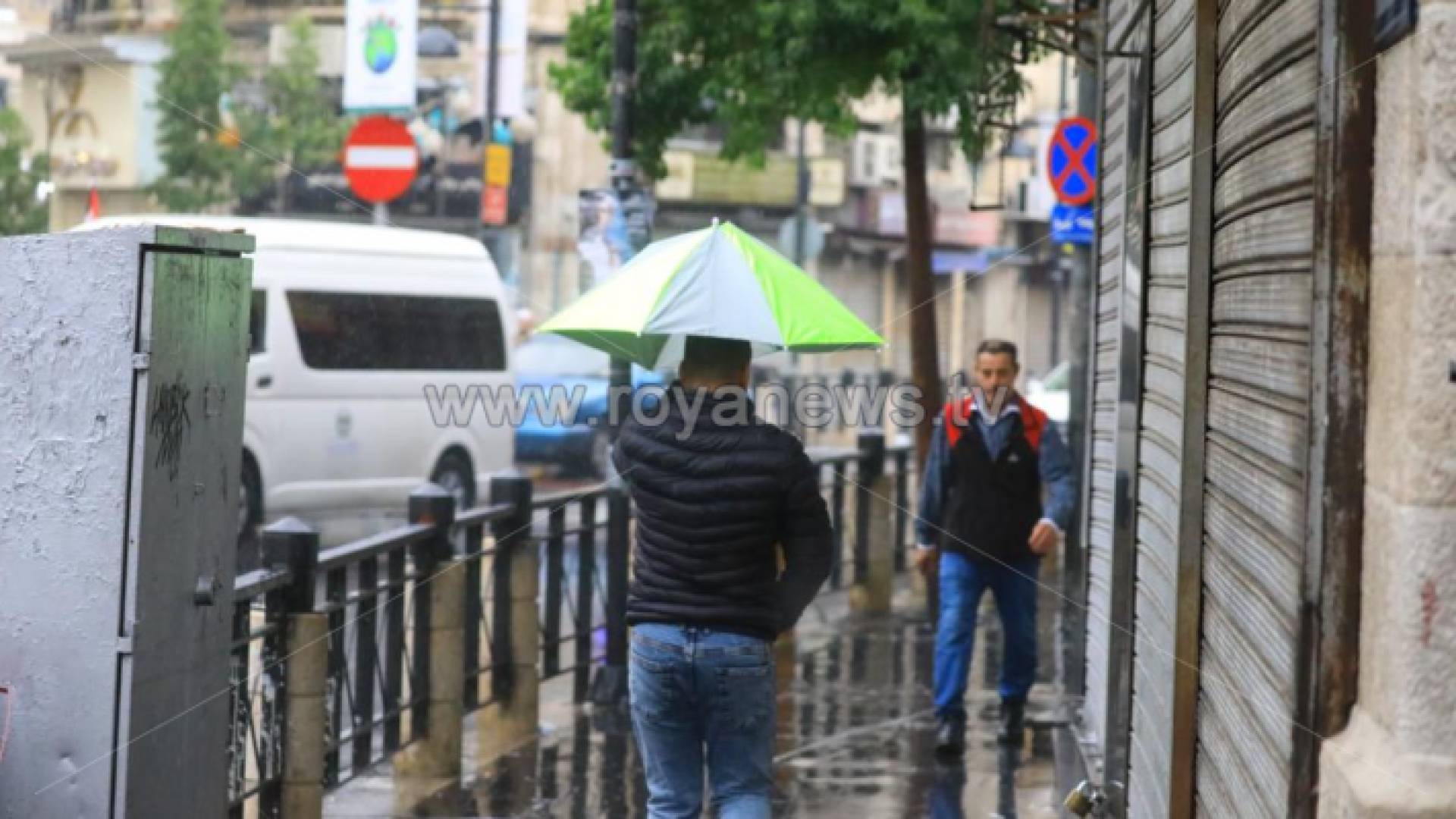 شخص يحمل مظلة تحت المطر في وسط البلد بالعاصمة عمان
