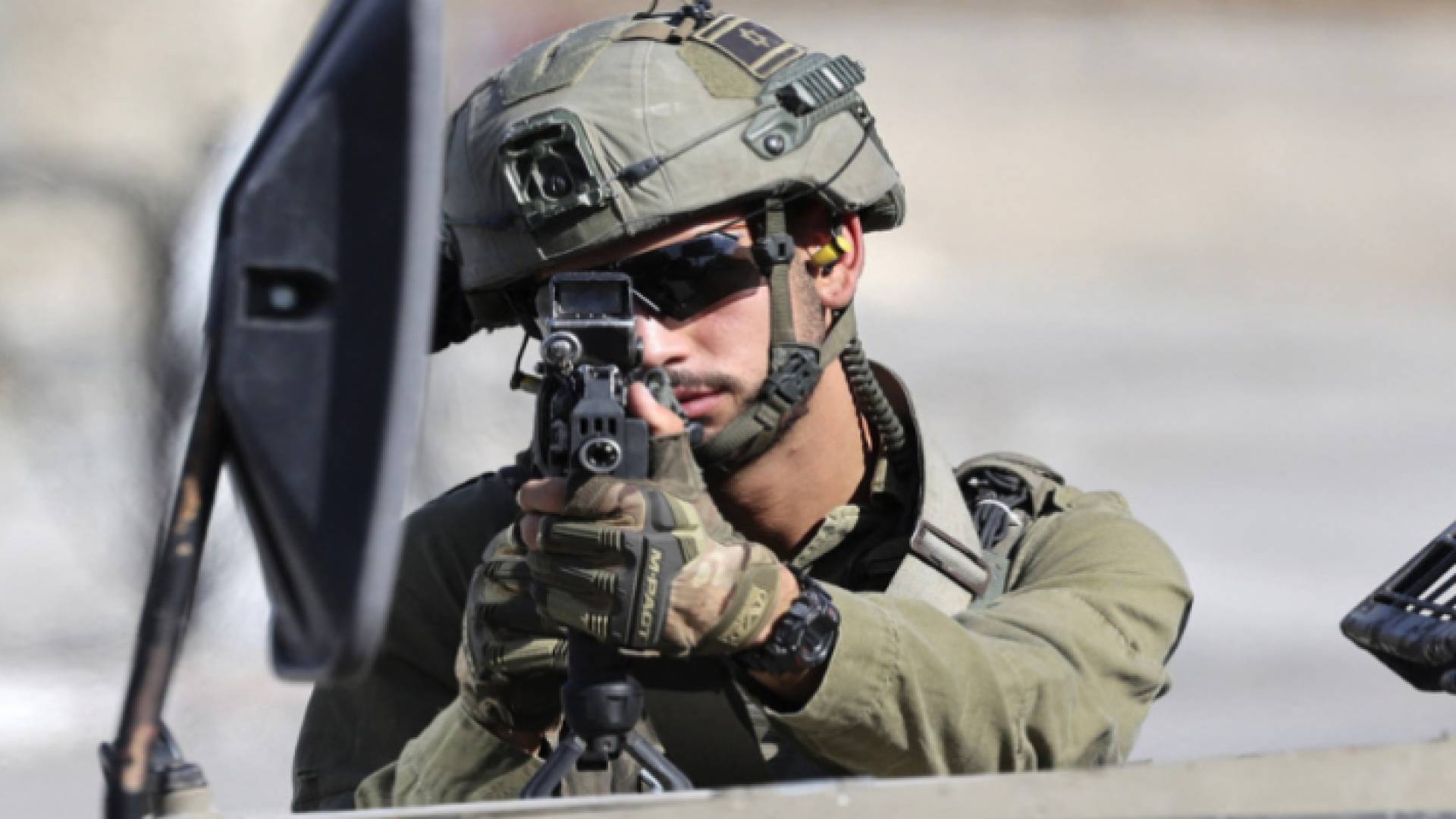 جندي في جيش الاحتلال يصوب بندقيته نحو فلسطينيين