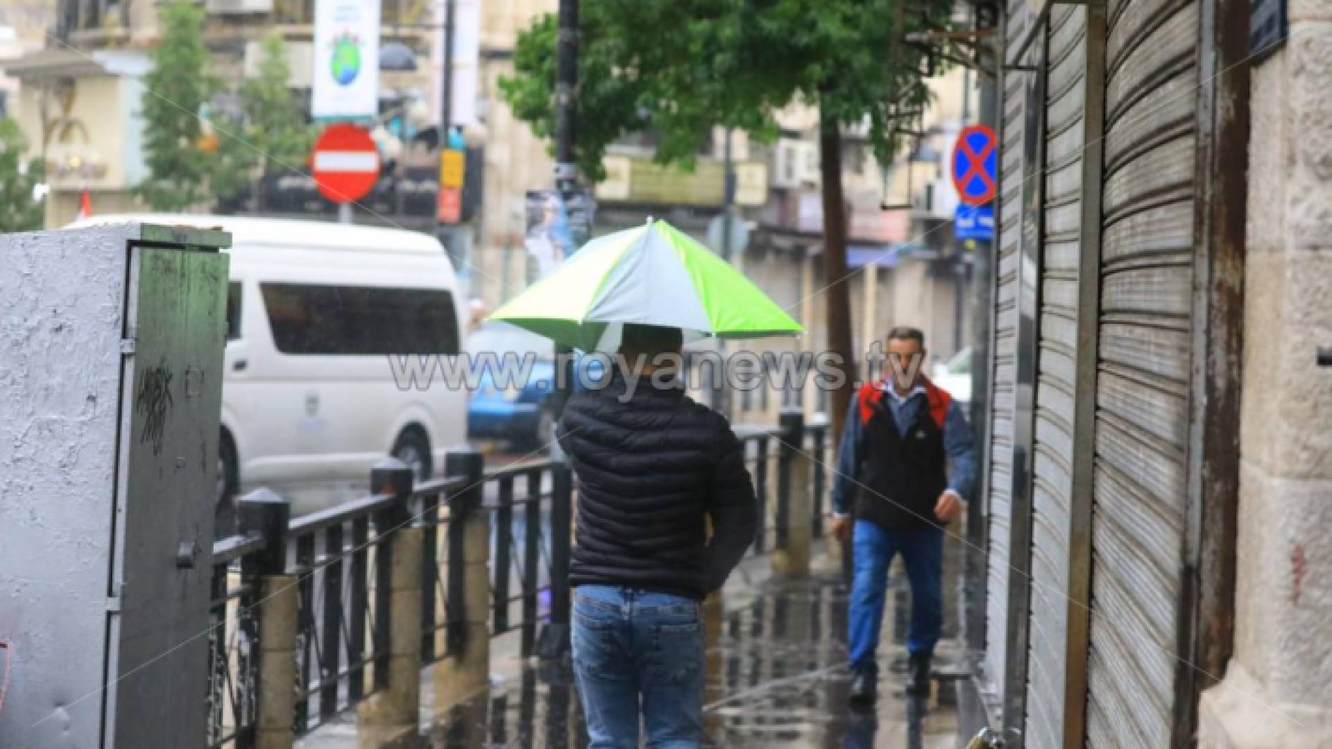 شخص يحمل مظلة تحت المطر في وسط البلد بالعاصمة عمان