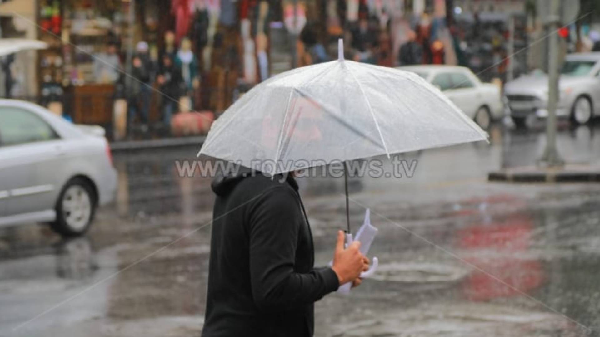 شخص يحمل مظليته ويقف تحت الأمطار في العاصمة عمان - أرشيفية