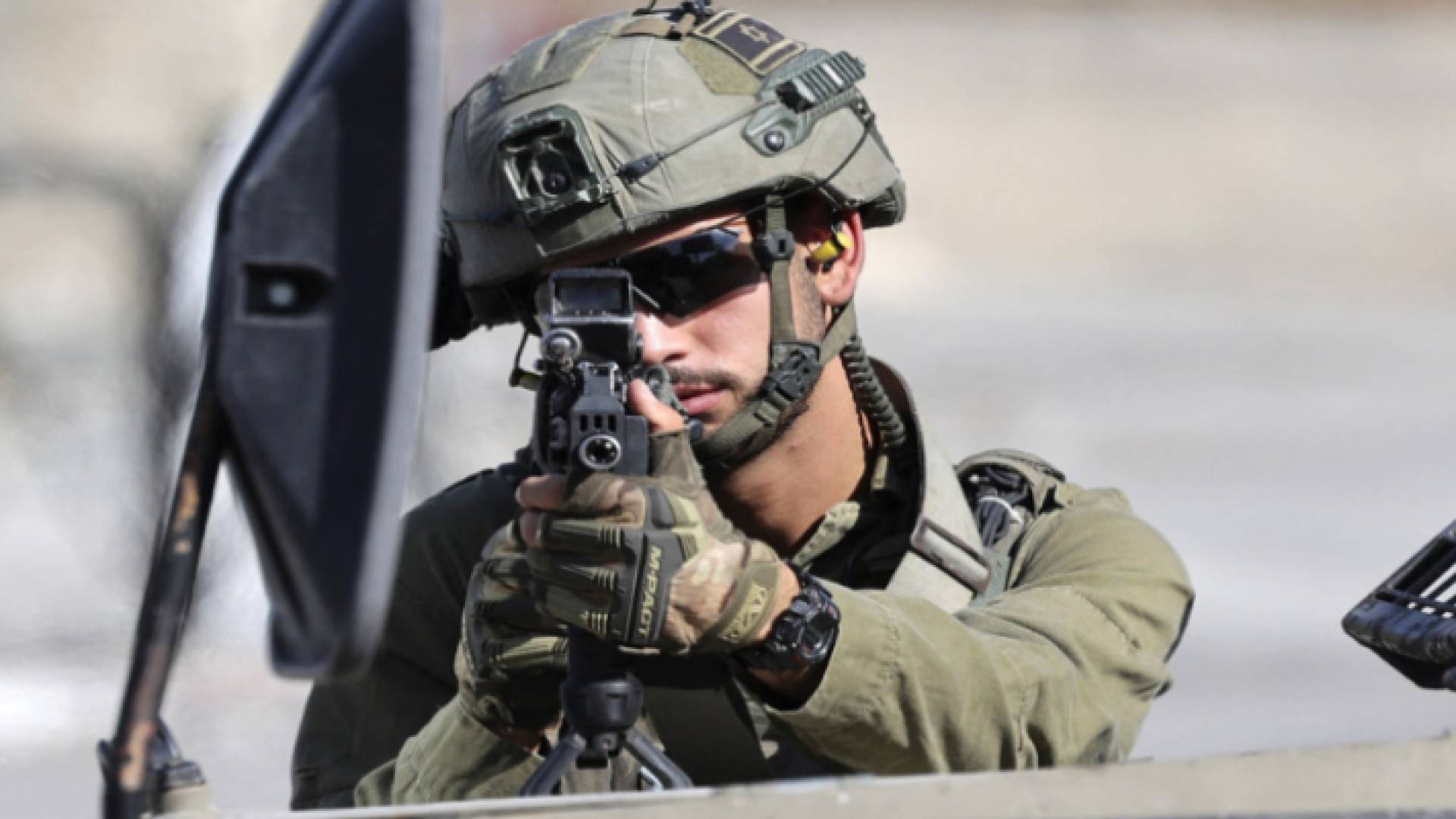 جندي في جيش الاحتلال يصوب بندقيته نحو فلسطينيين