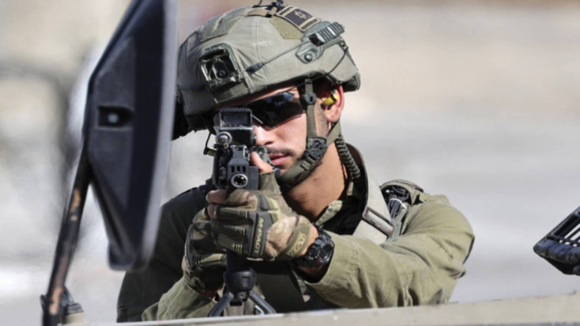 جندي في جيش الاحتلال يصوب بندقيته نحو فلسطينيين