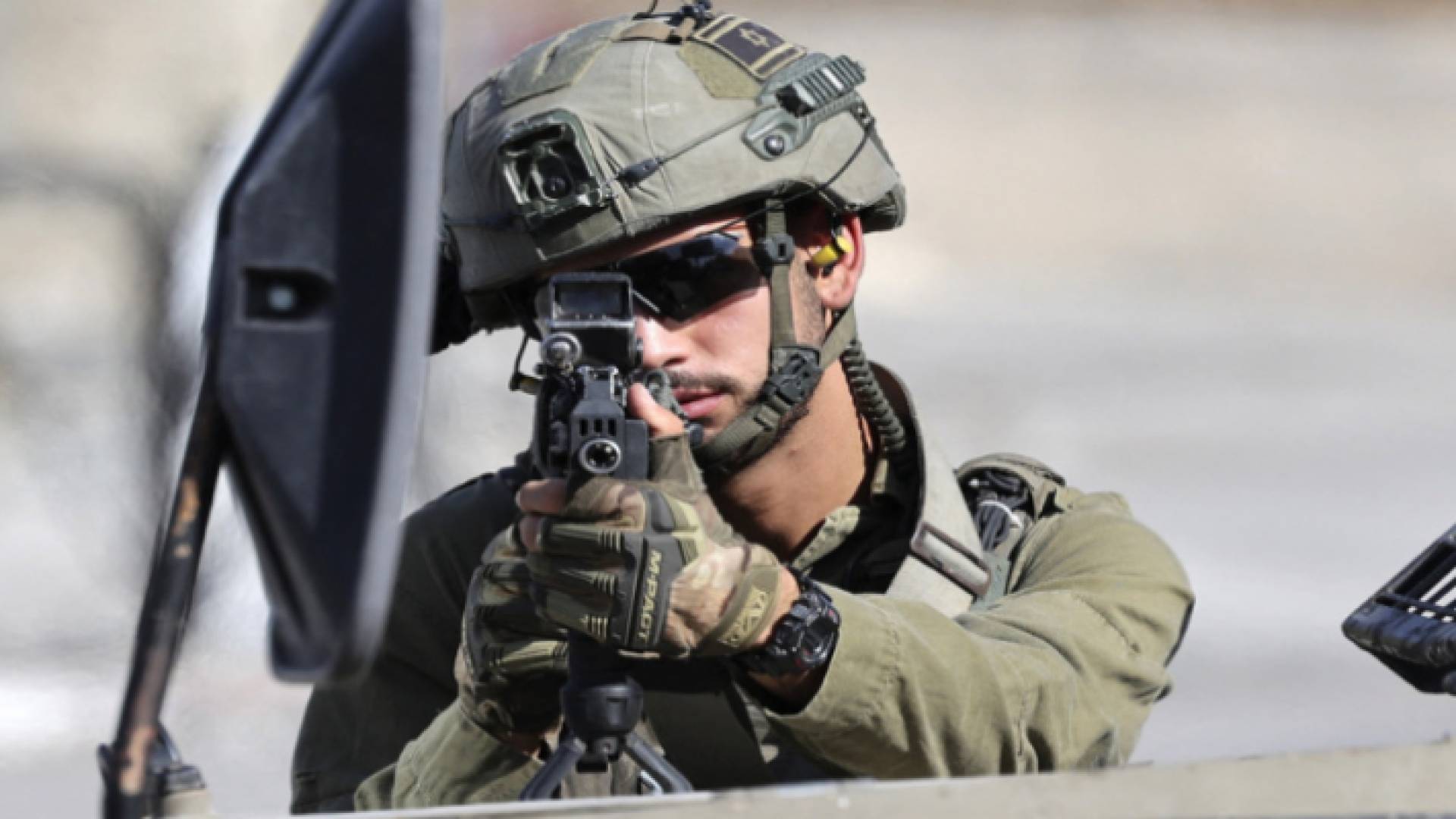 جندي في جيش الاحتلال يصوب بندقيته نحو فلسطينيين