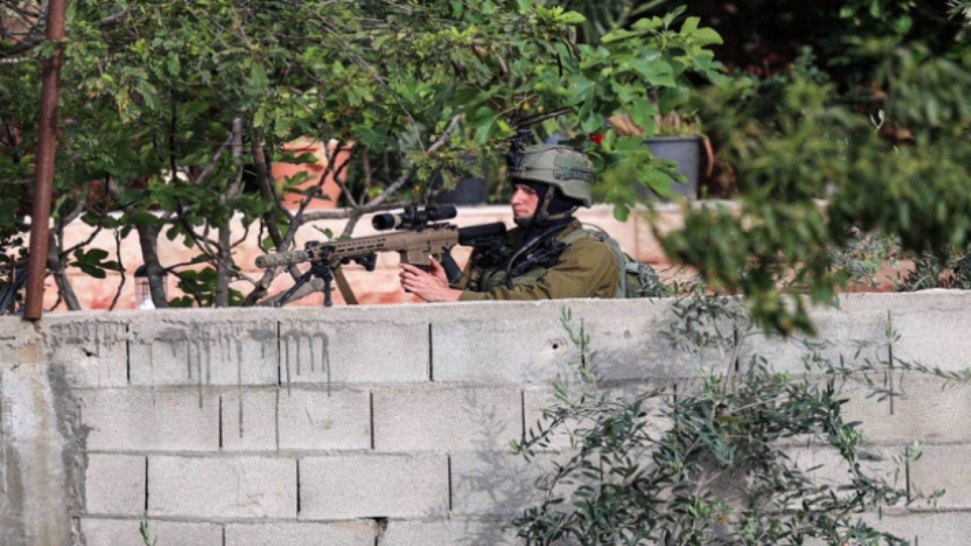 عنصر في جيش الاحتلال يصوب بندقيته نحو فلسطينيين