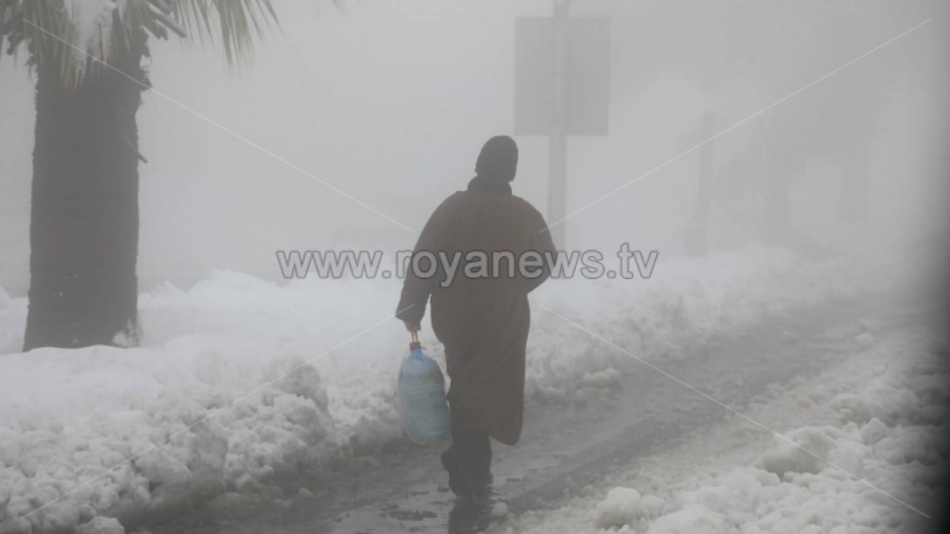 رجل يسير وسط الثلوج