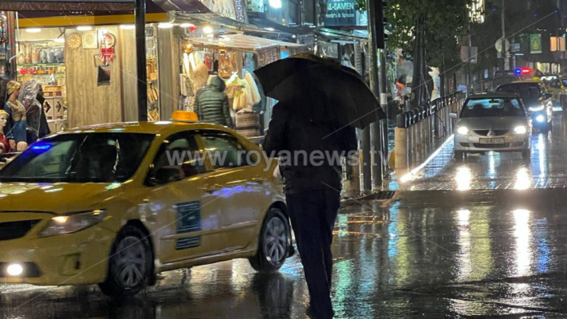 شخص يحمل مظلة في أحد شوارع العاصمة عمان