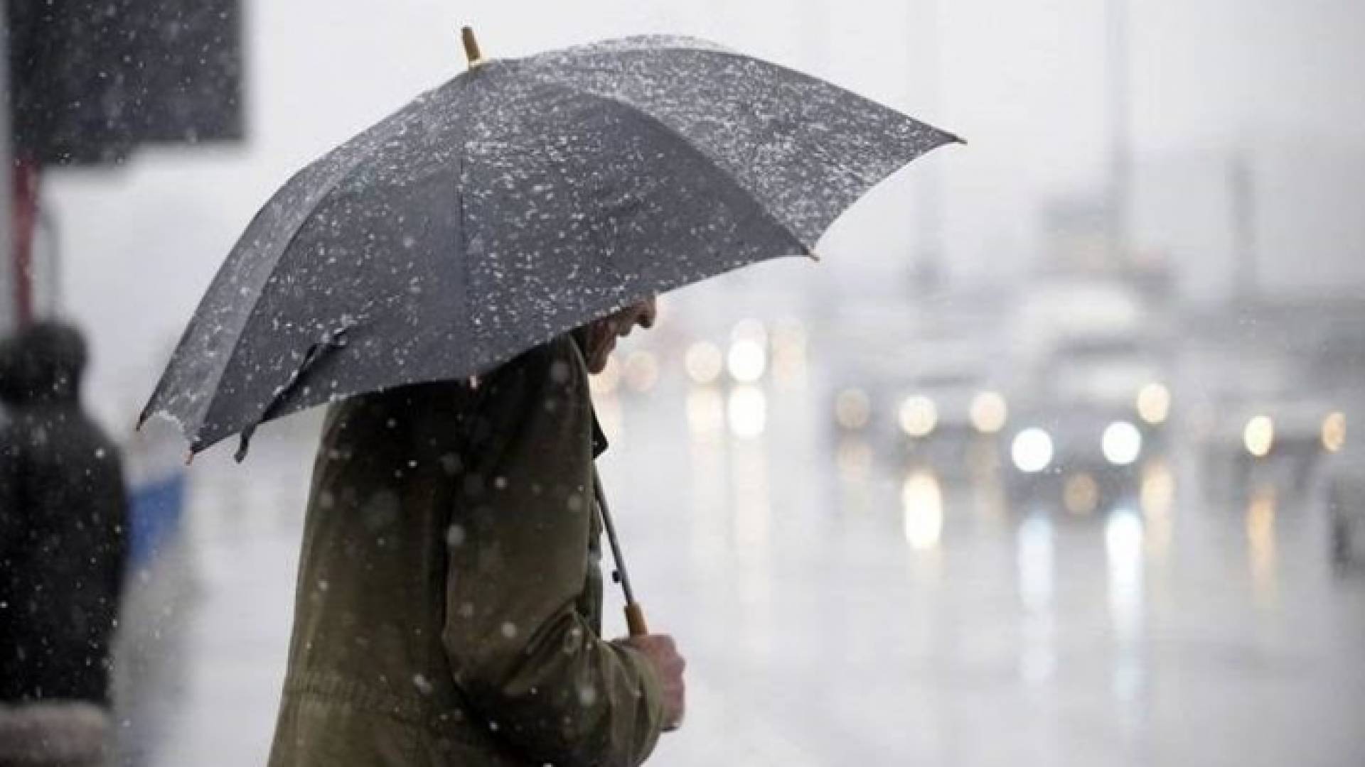 مواطن يحمل مظلية في أثناء تساقط الأمطار الغزيرة