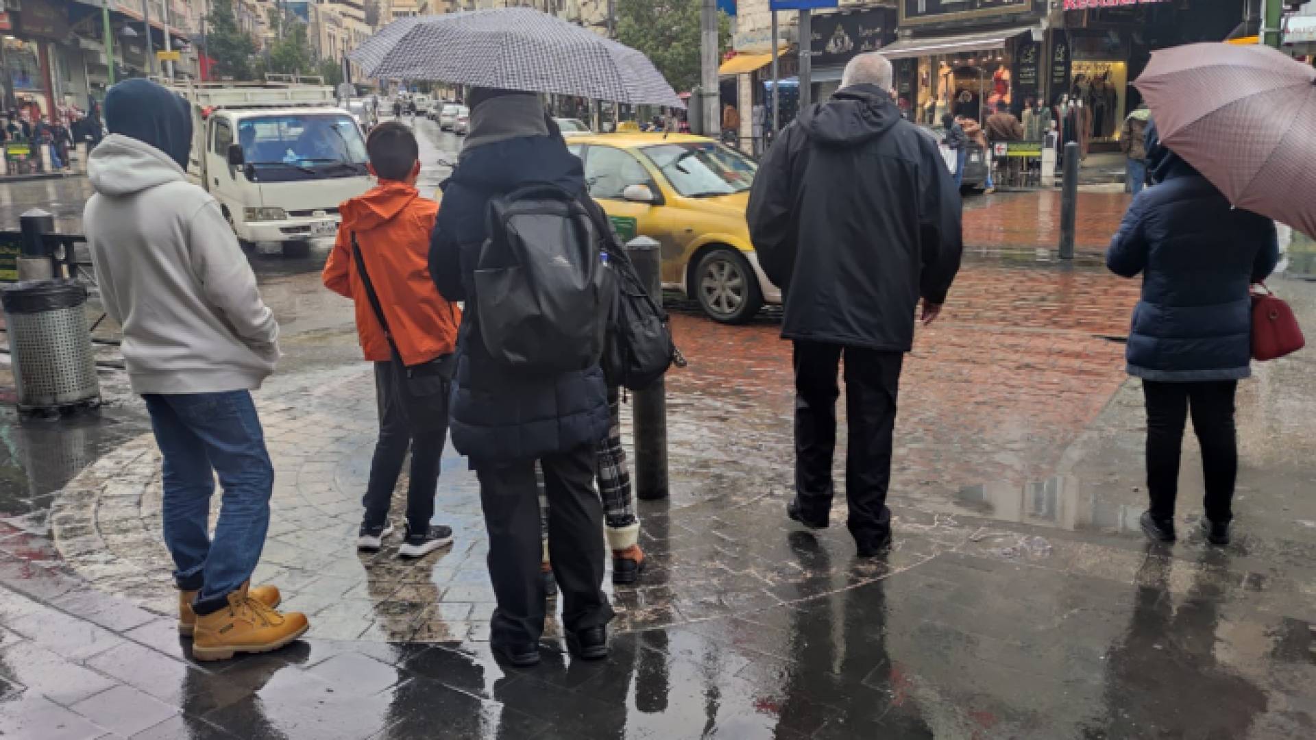 مواطنون يقفون تحت المطر في العاصمة عمان