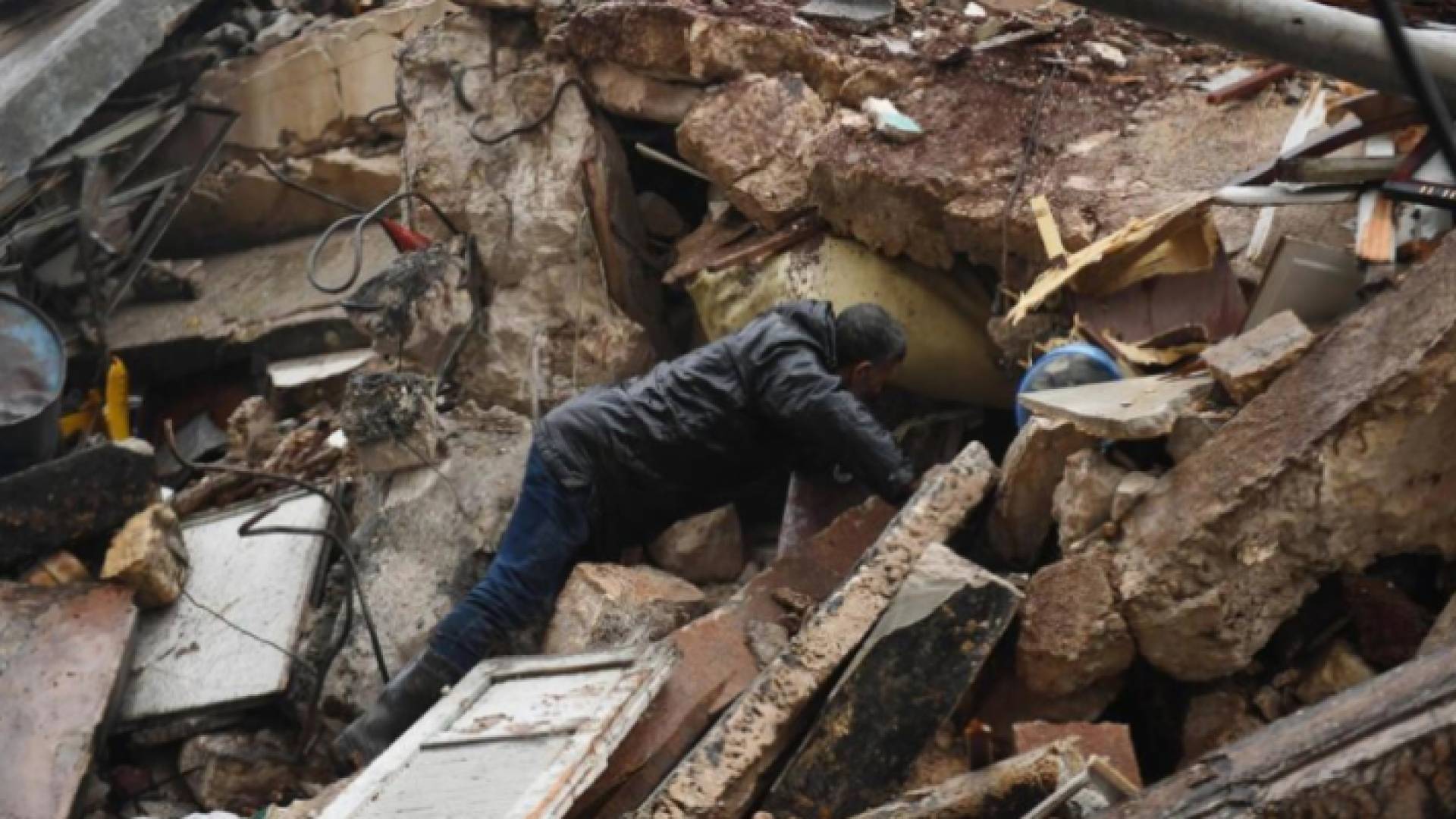 رجل يبحث عن ناجين بين أنقاض مبنى منهار في حلب بعد الزلزال المدمر