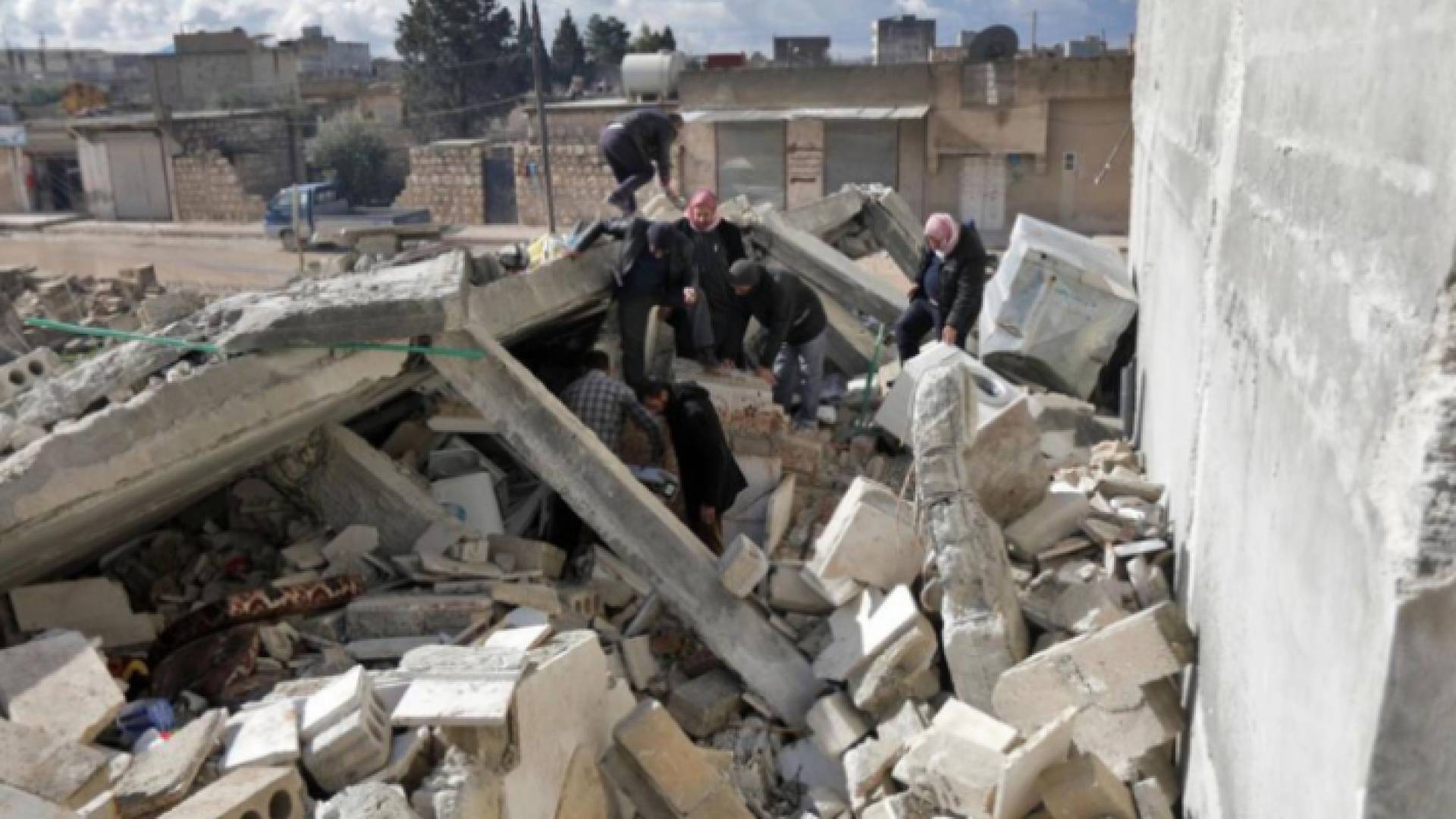 سوريون يبحثون بين أنقاض مبنى منهار عند الحدود مع تركيا