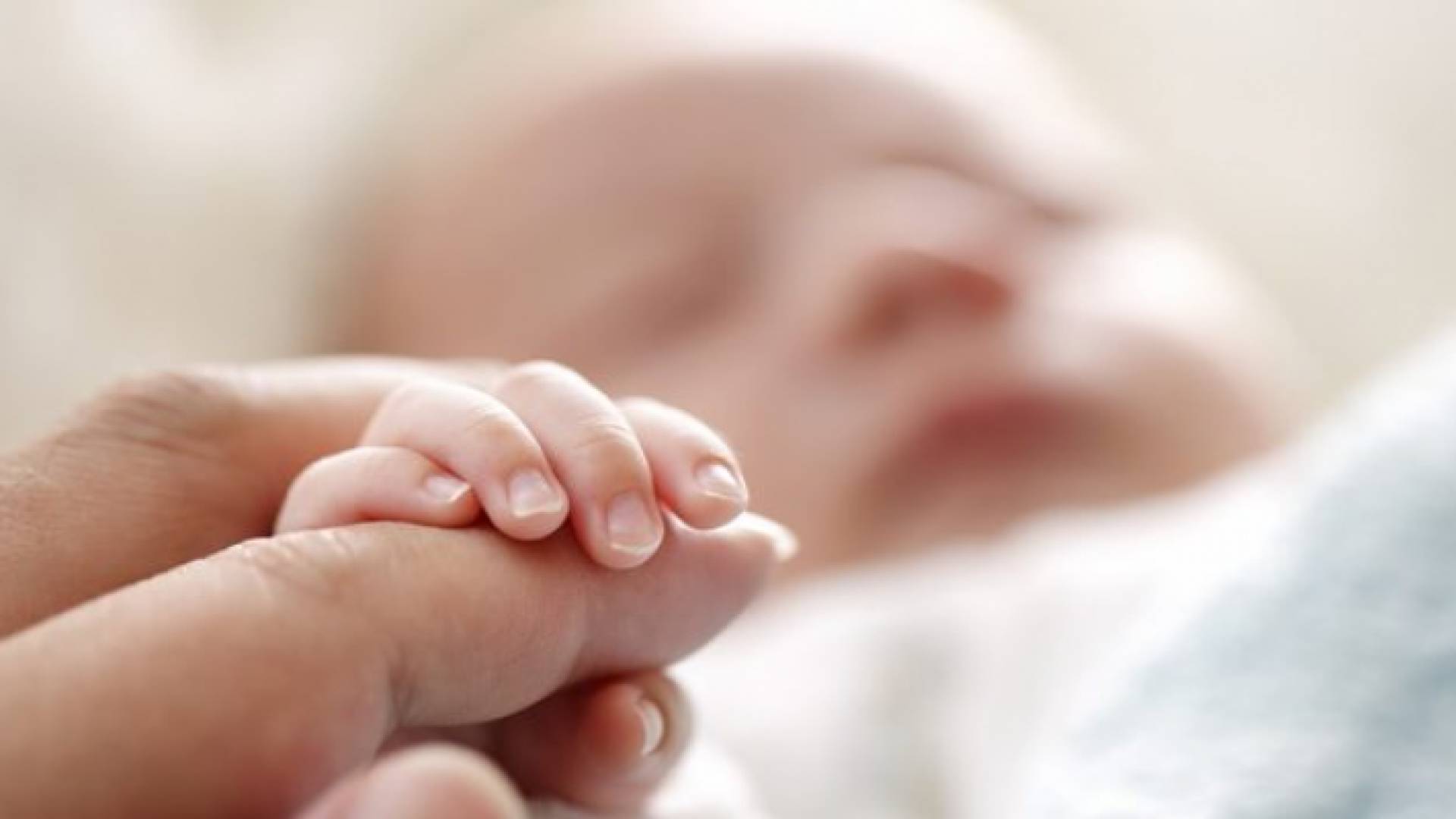صورة تعبيرية لرضيع يمسك بيد شخص