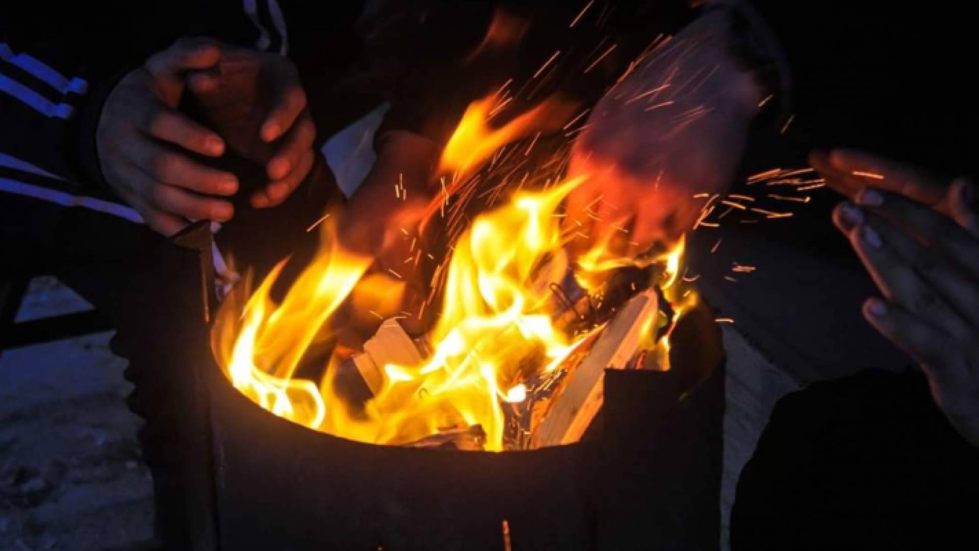 أشخاص يستخدمون موقد الحطب للتدفئة