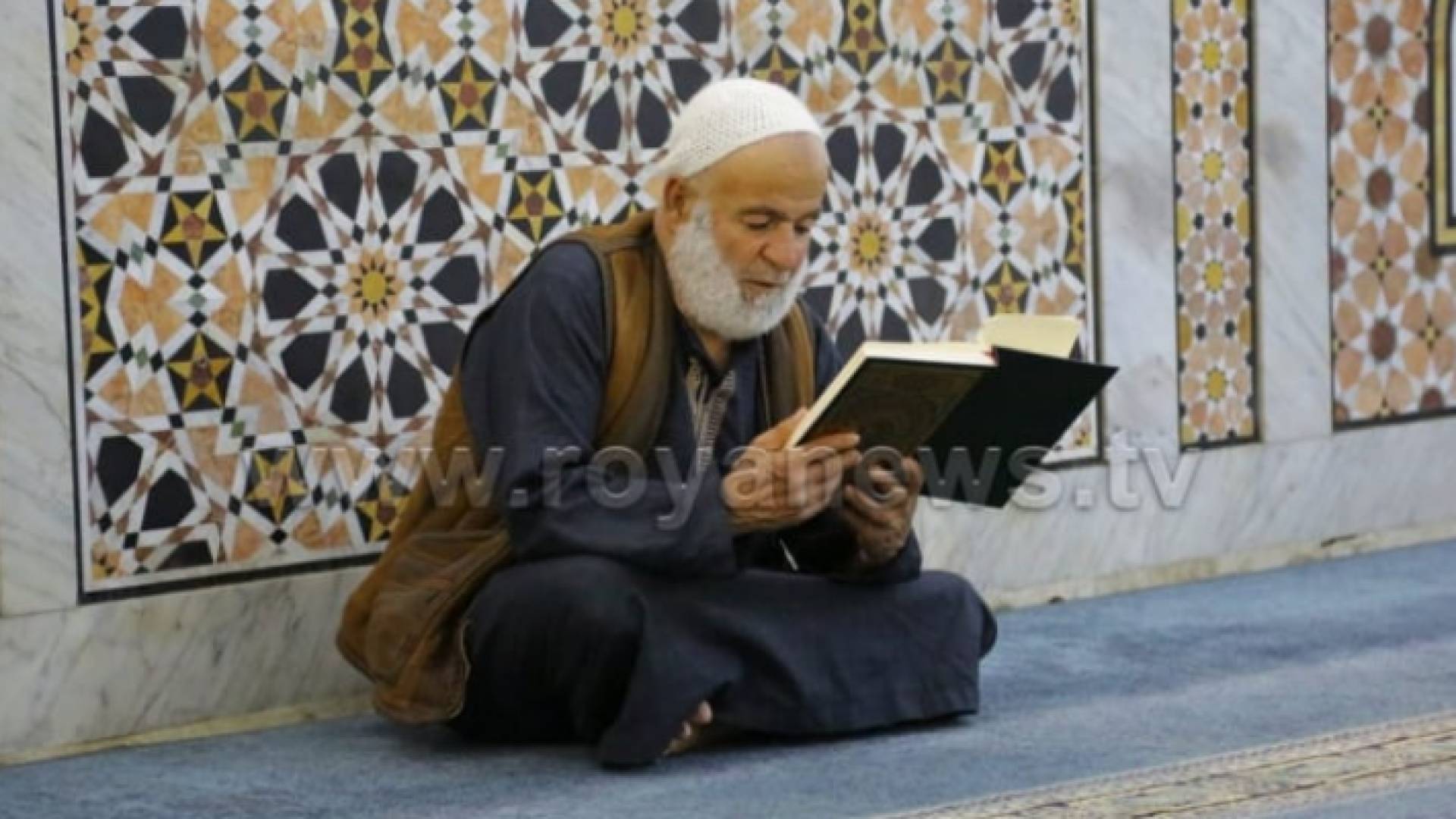 مسن يقرأ القرآن الكريم في أحد المساجد
