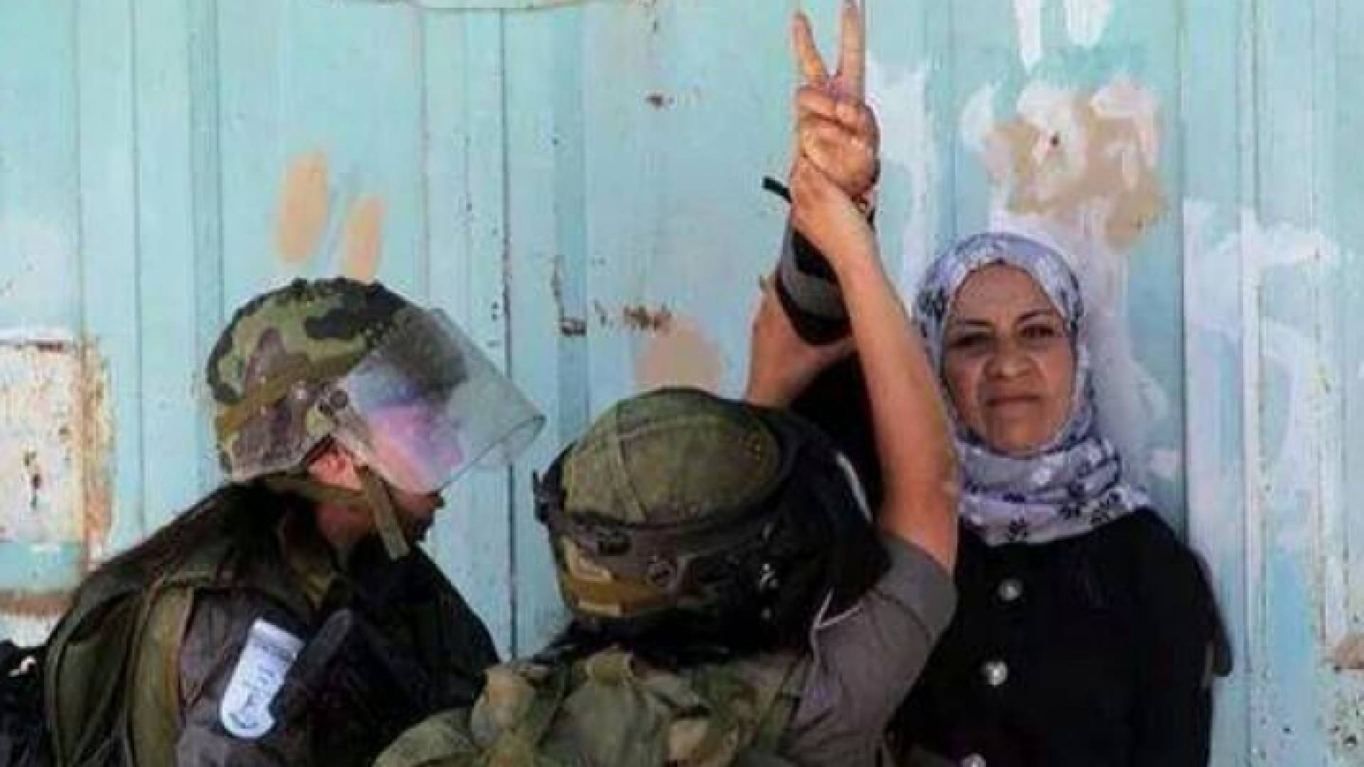 سيدة فلسطينية ترفع إشارة النصر في وجه قوات الاحتلال