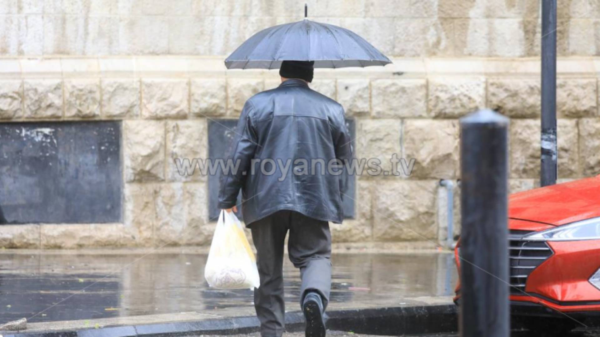 شخص يحمل مظلة في أحد شواع العاصمة عمان