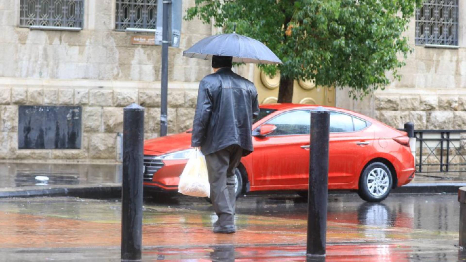 شخص يحمل مظلة في أحد شواع العاصمة عمان