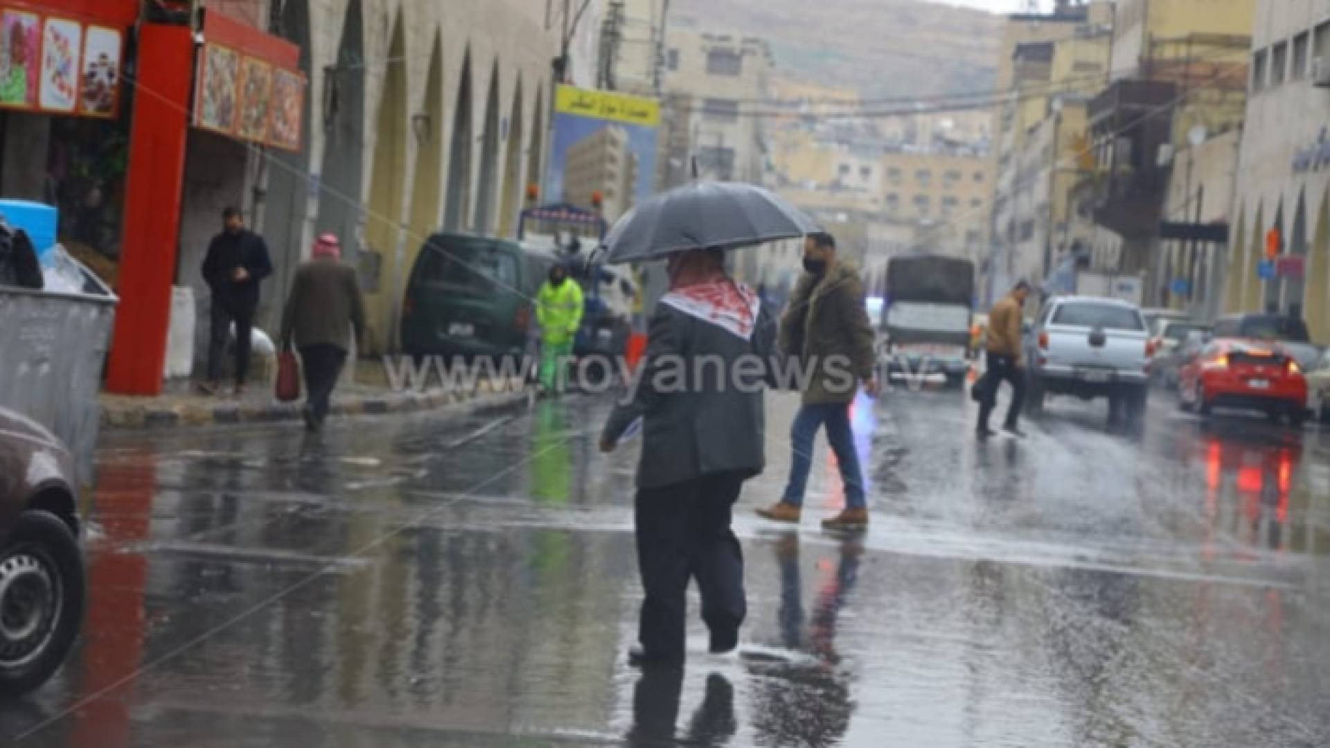 مواطن يسير تحت الأمطار في منطقة وسط البلع في عمان