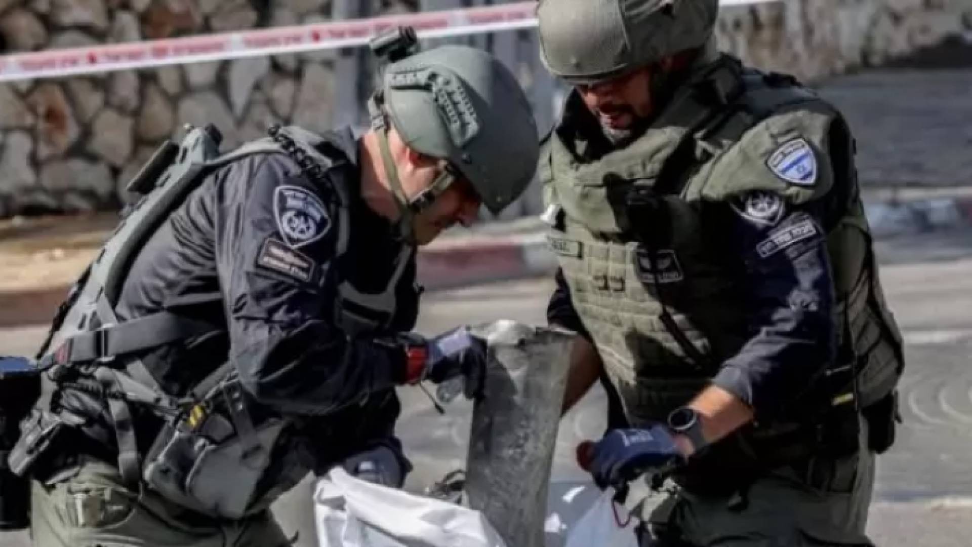 جنديان "إسرائيليان" يضعان شظية صاروخ سقط في شمال فلسطين المحتلة بعد أن انطلق من لبنان