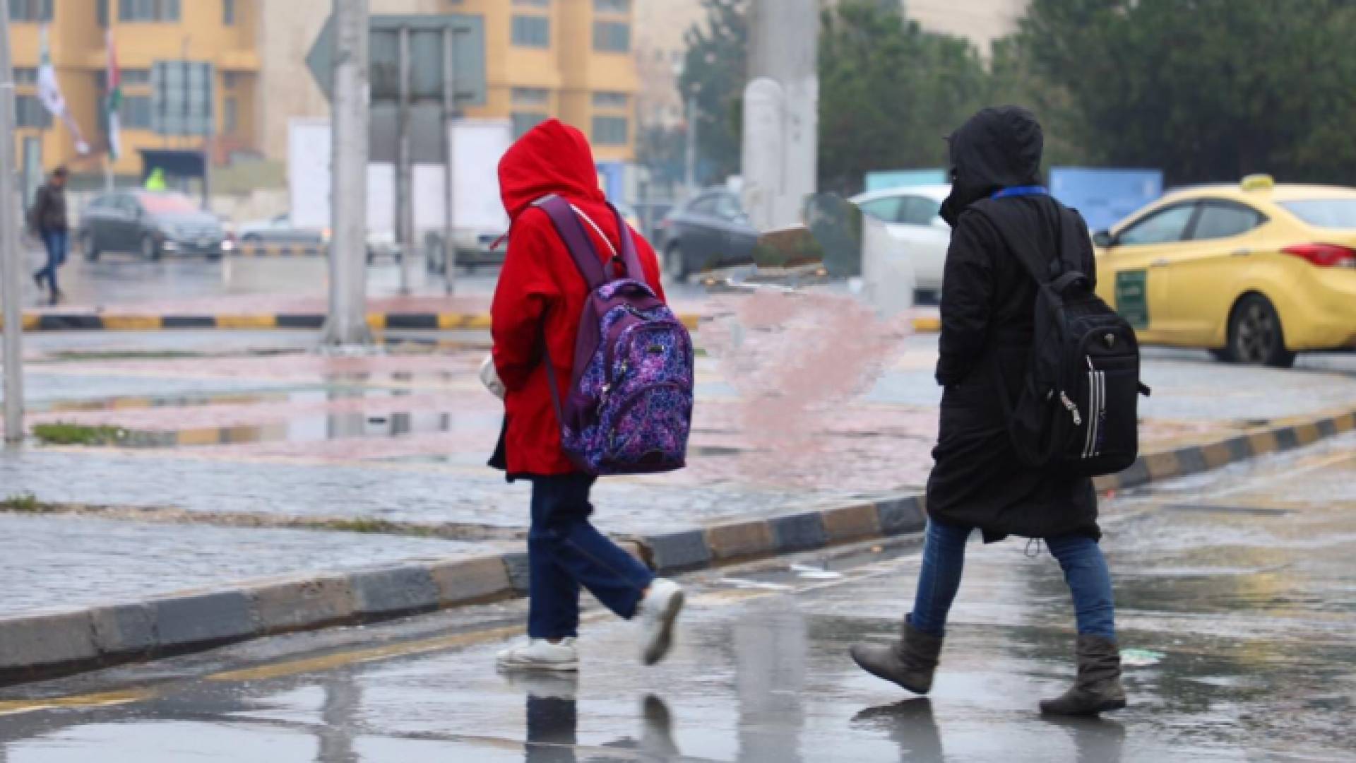 طلبة مدارس يذهبون إلى مدارسهم وسط تساقط الأمطار