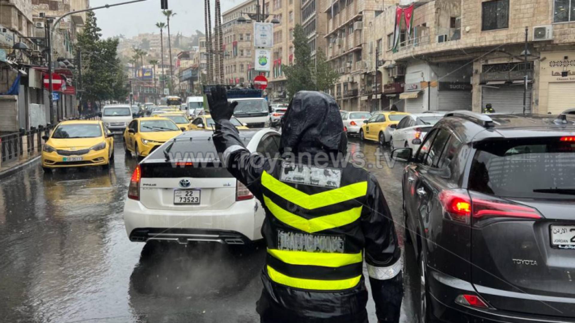 شرطي سير يقوم بوظيفته وسط الأمطار الغزيرة في عمان