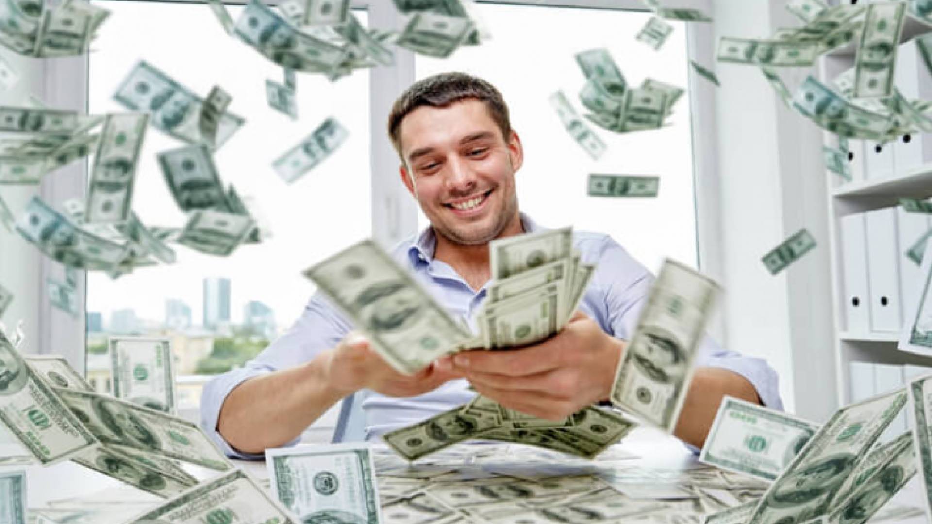 صورة تعبيرية لشخص امام مجموعة من الأموال من فئة الدولار