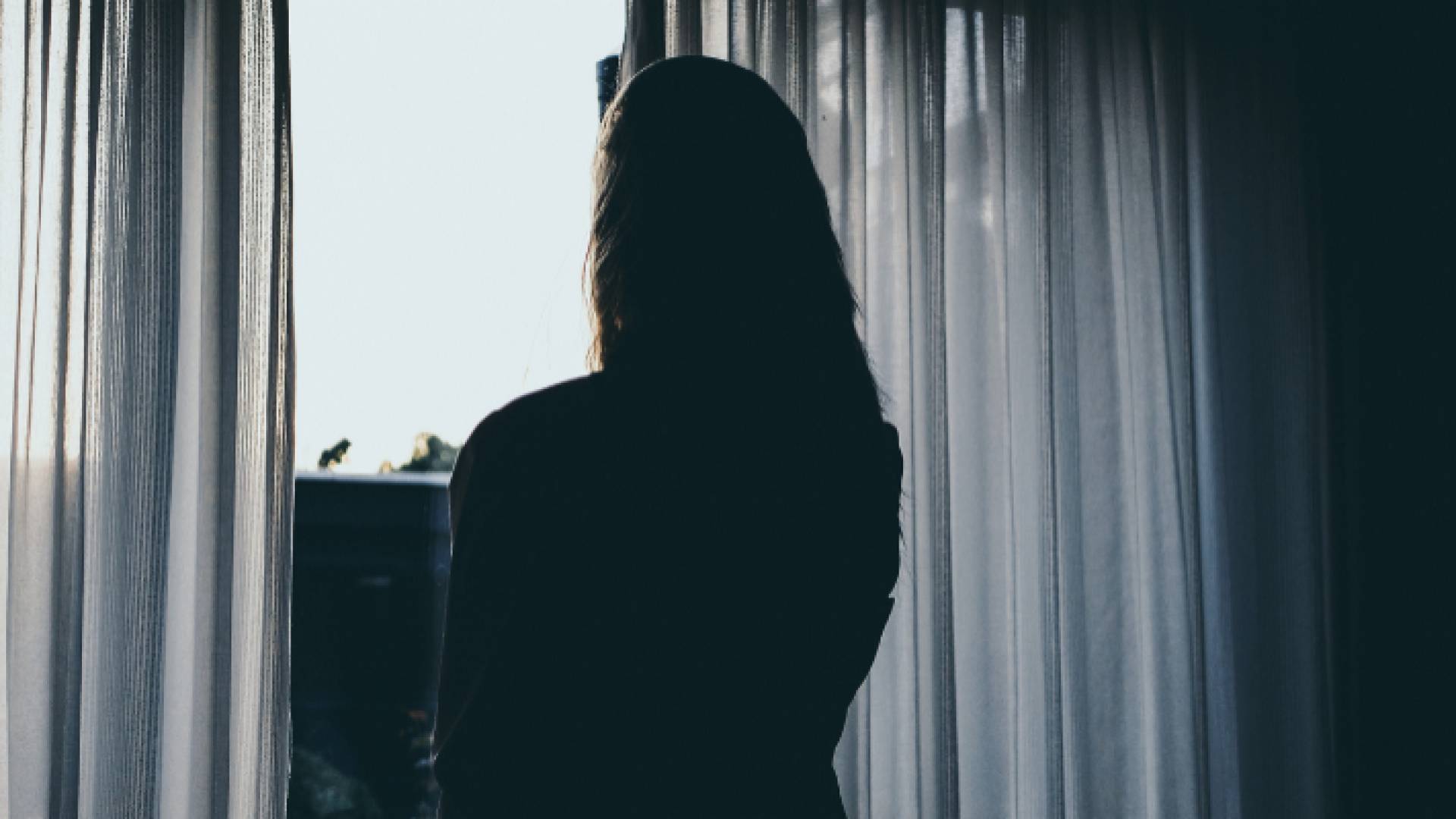 صورة تعبيرية لسيدة تقف أمام الشباك