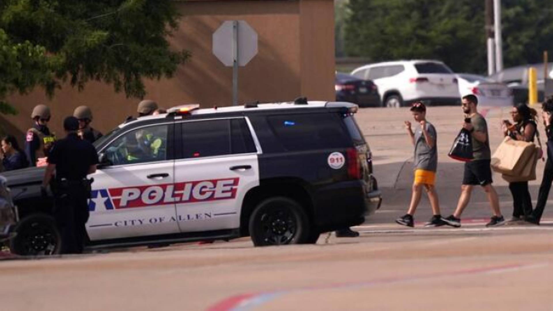 أشخاص يرفعون أيديهم أثناء مغادرتهم لمركز التسوق بعد ورود تقارير عن إطلاق نار