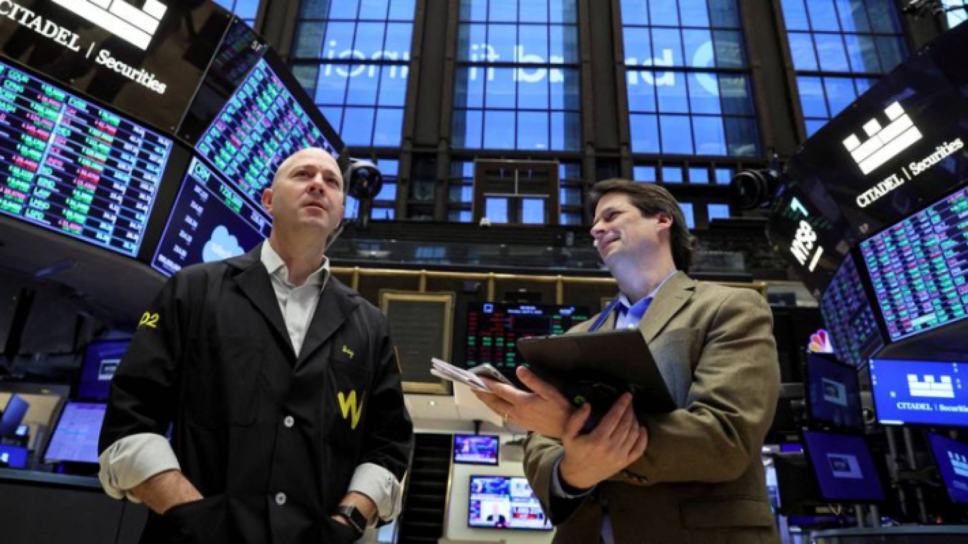 صورة لشخصين يتابعان مؤشرات الأسهم الأمريكية