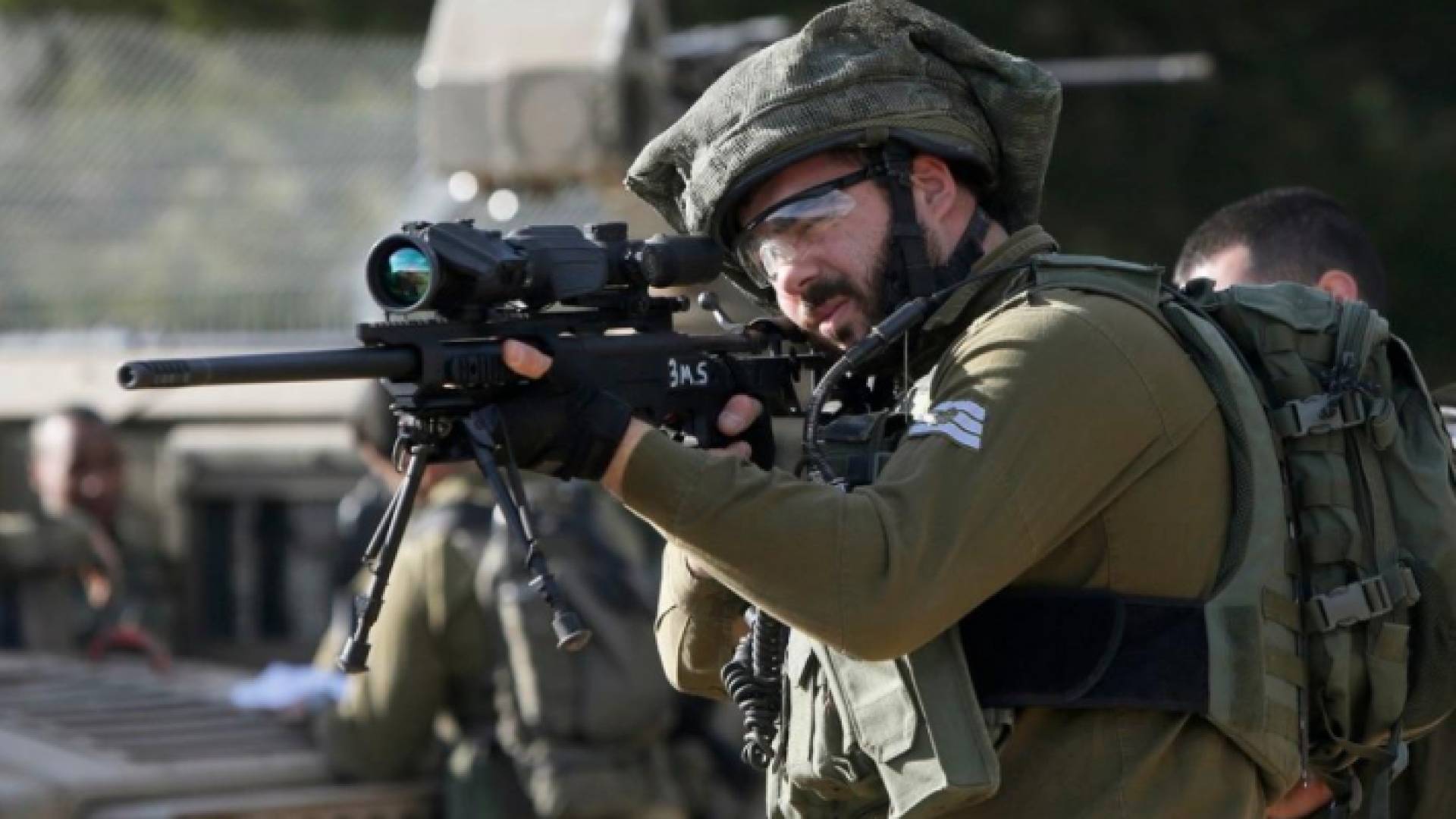 جندي من قوات الاحتلال الإسرائيلي يصوب سلاحه نحو فلسطينيين