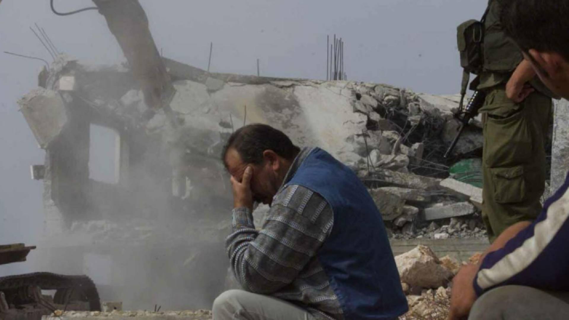 فلسطيني يجلس أمام منزله بعد هدمه