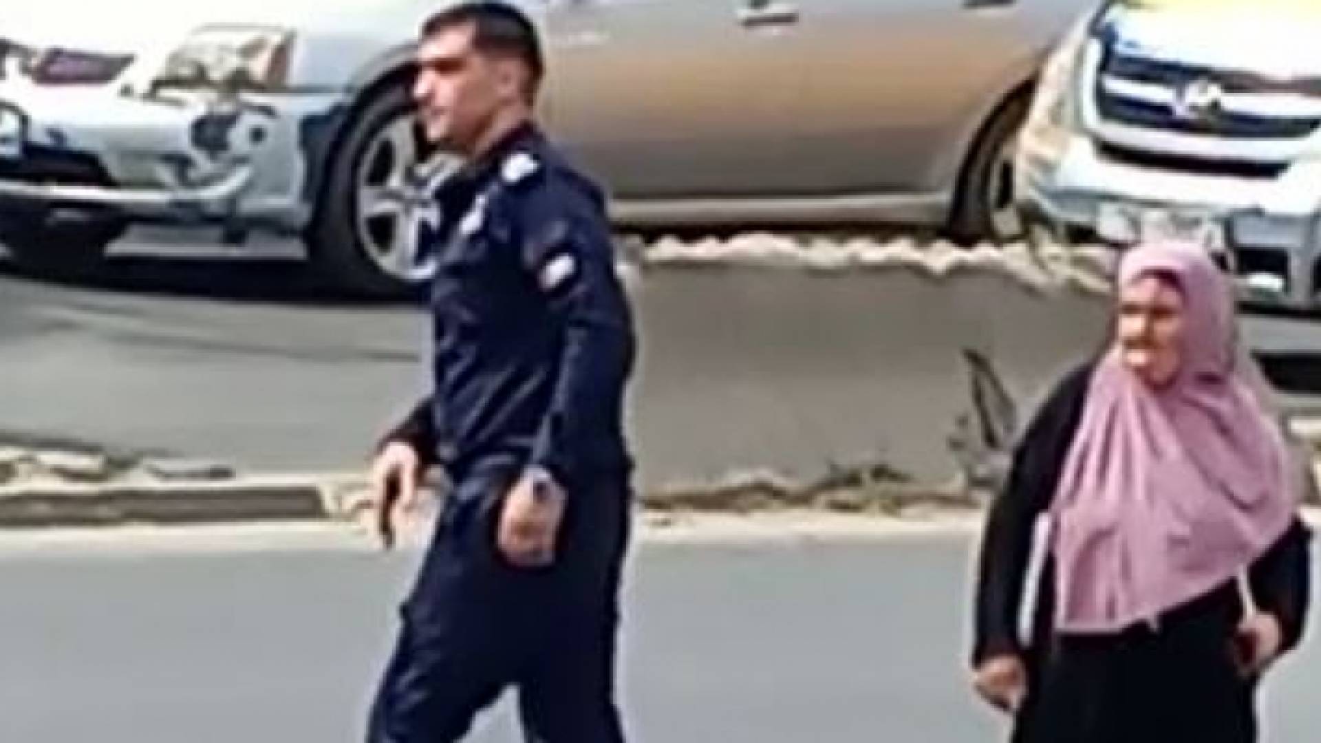 رجل أمن يوقف حركة المرور لتأمين عبور مسنة