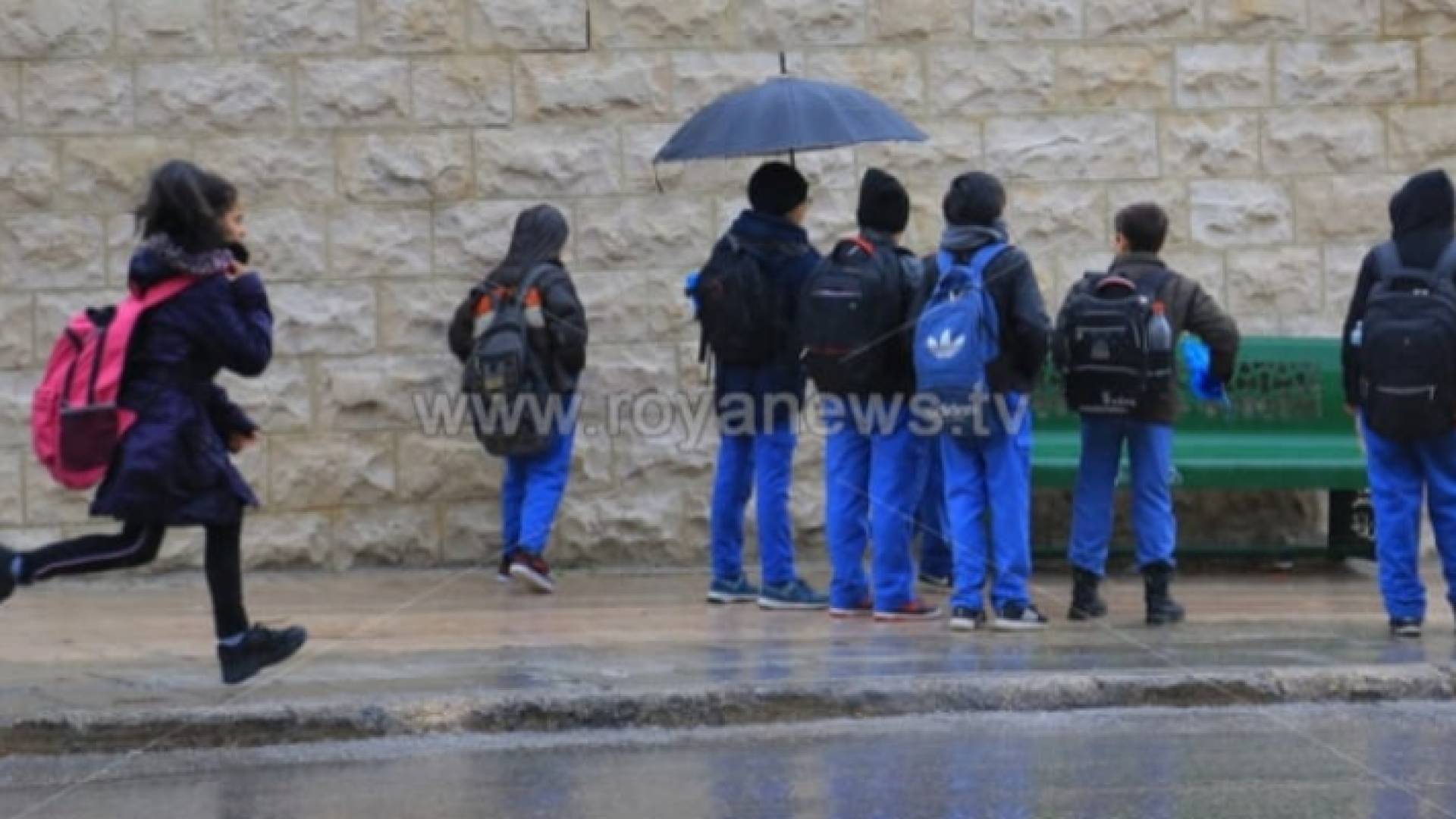 طلبة مدارس في أحد الشوارع أثناء هطول الأمطار