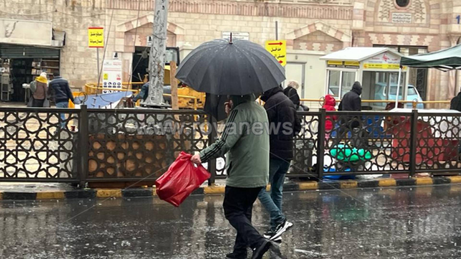 أشخاص يحملون مظلة في العاصمة عمان