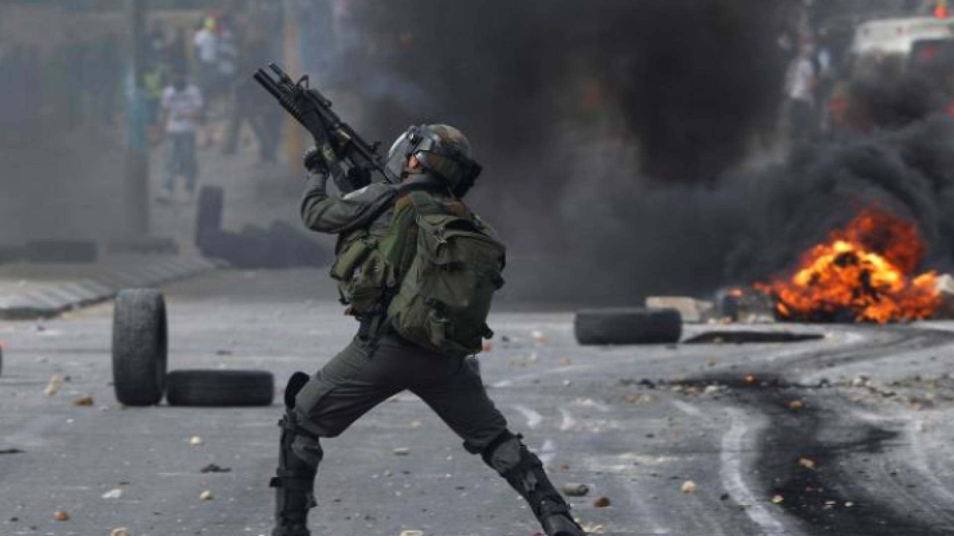 جندي من قوات الاحتلال الإسرائيلي يصوب سلاحه نحو فلسطينيين