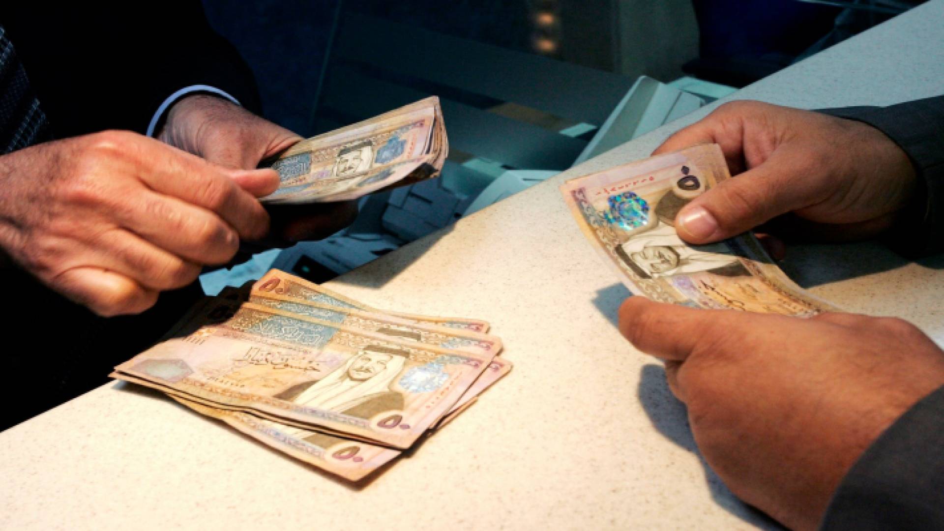 أشخاص يحملون عملة ورقية