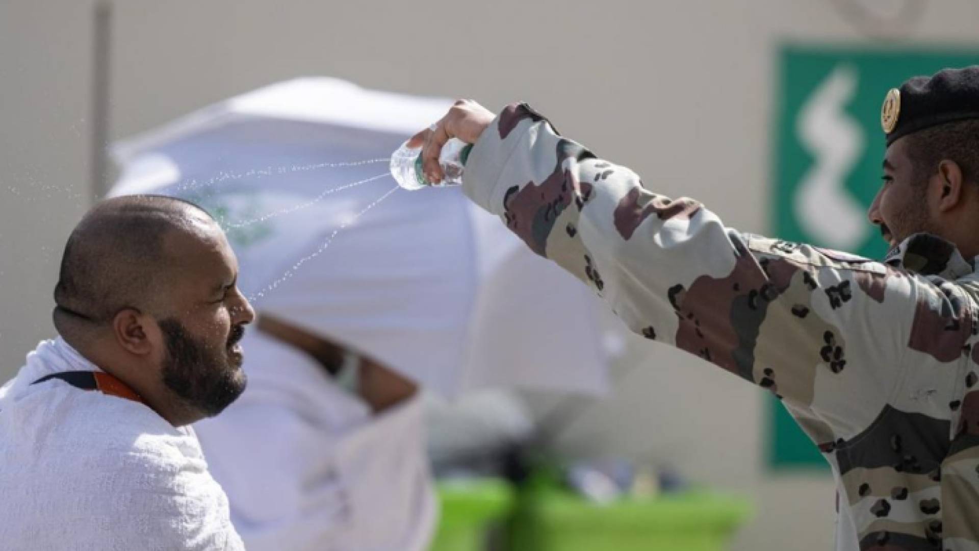 رجل أمن سعودي يرش المياه بوجه حاج لمواجة ارتفاع الشمس