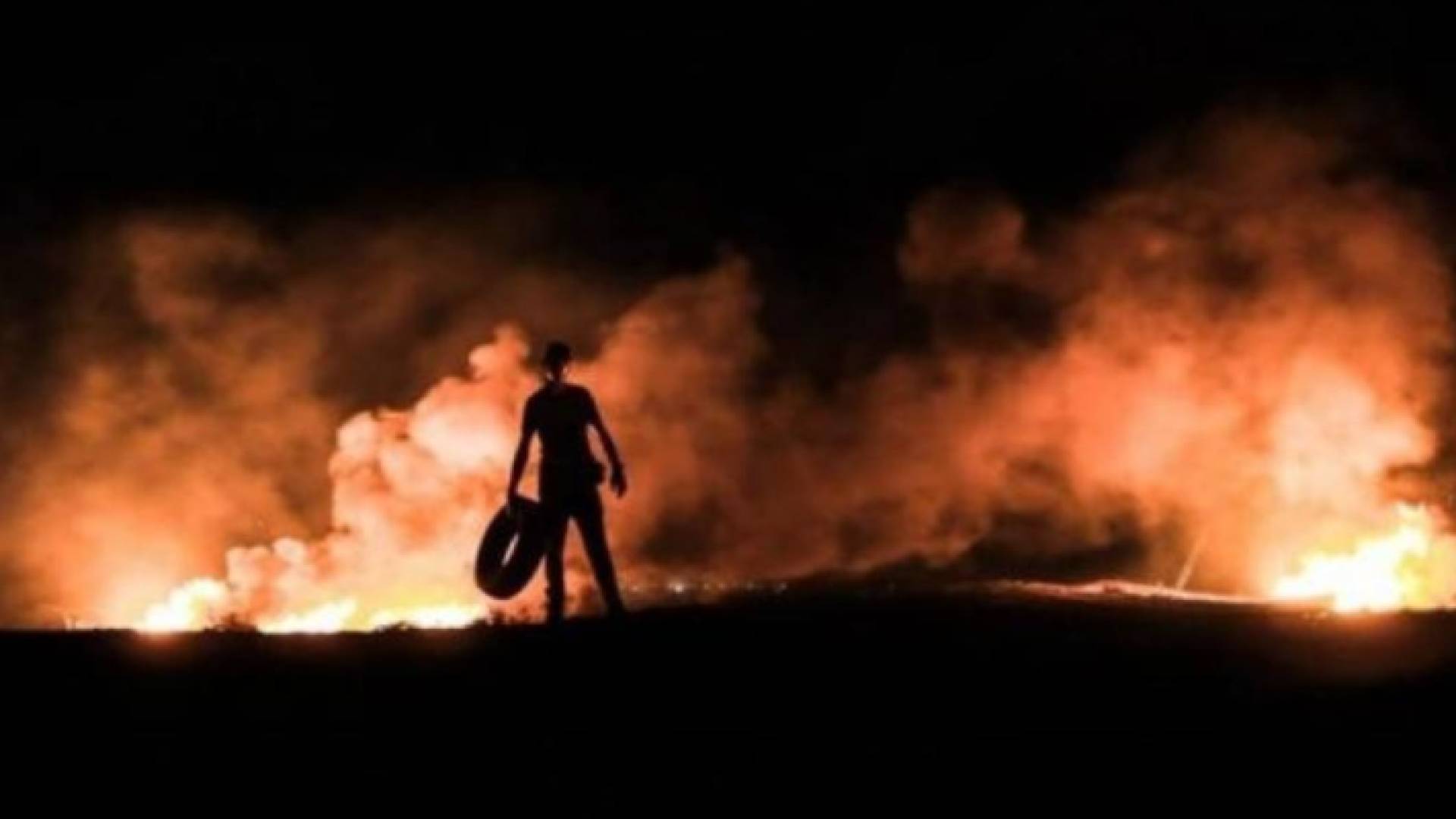 صورة لغزيين يشعلون نار بالقرب من السياج الفاصل - أرشيفية