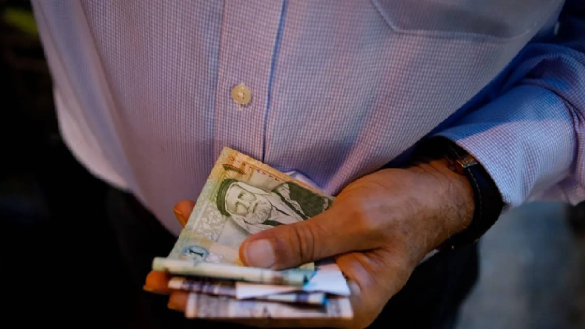 صورة أرشيفية لشخص يحمل عملة ورقية