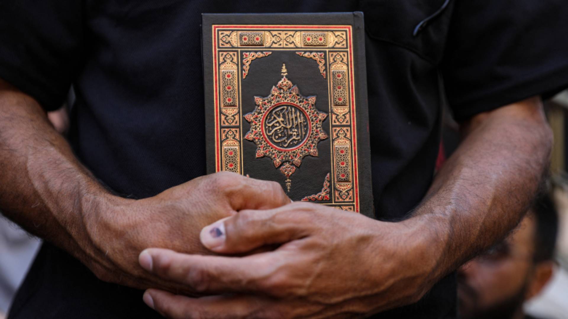 شخص يحمل القرآن الكريم