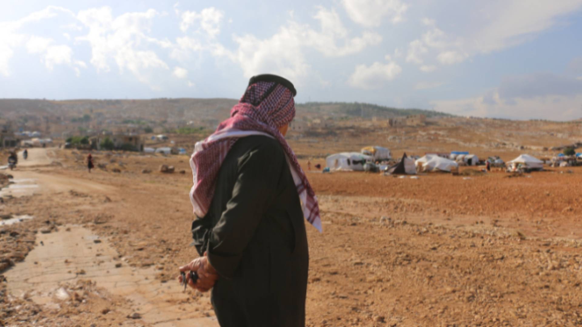 رجل يقف أمام أحدى مخيمات اللاجئين