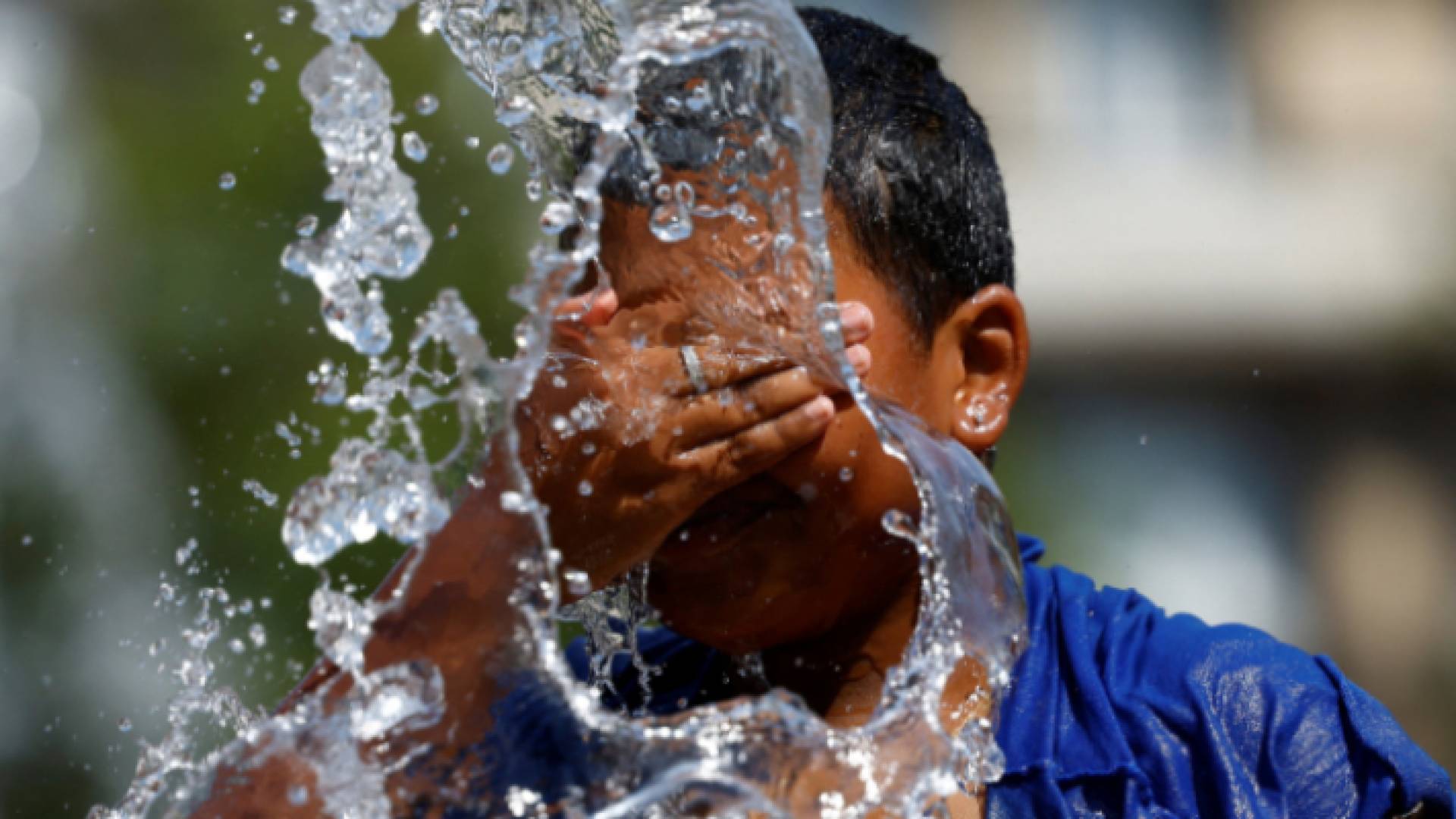 شخض يسكب الماء على وجهه في الأجواء الحارة