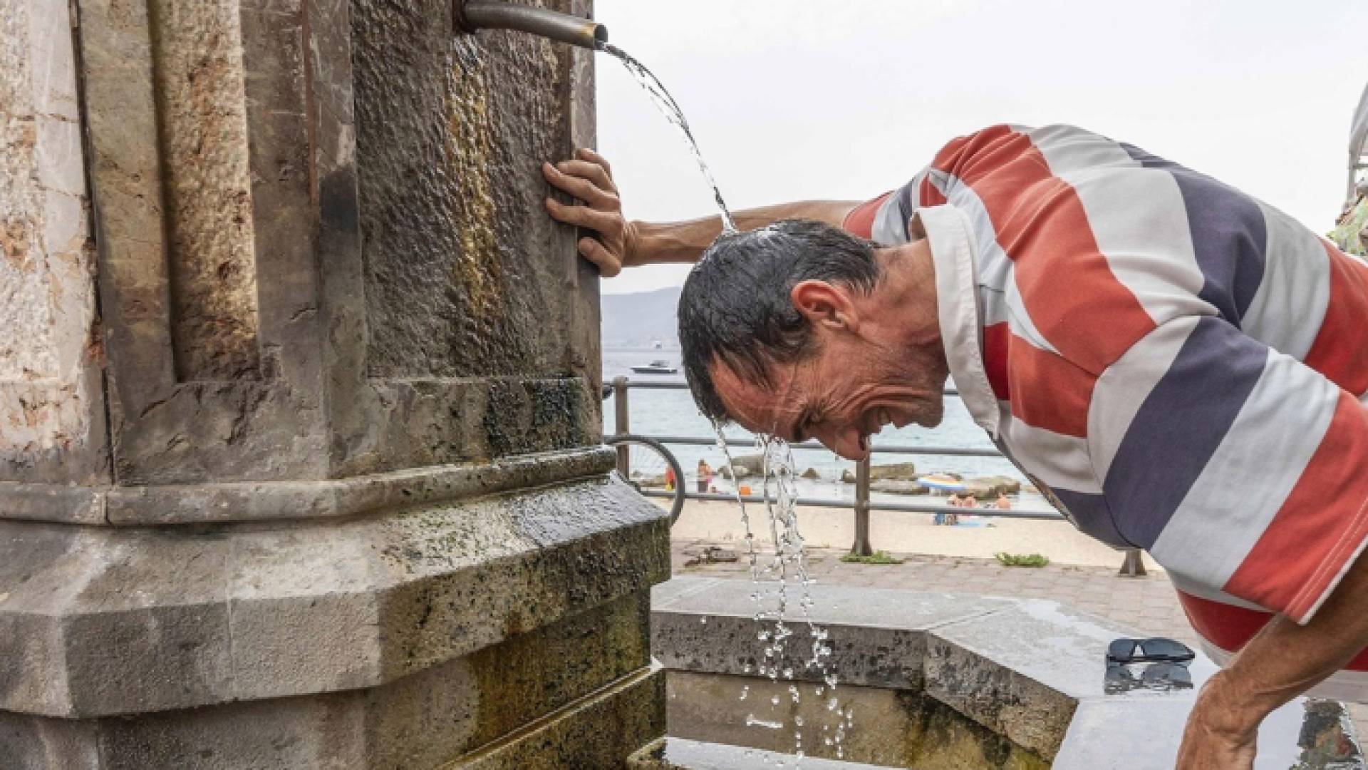 شخص يغسل رأسه بالماء في أحد شوارع إيران