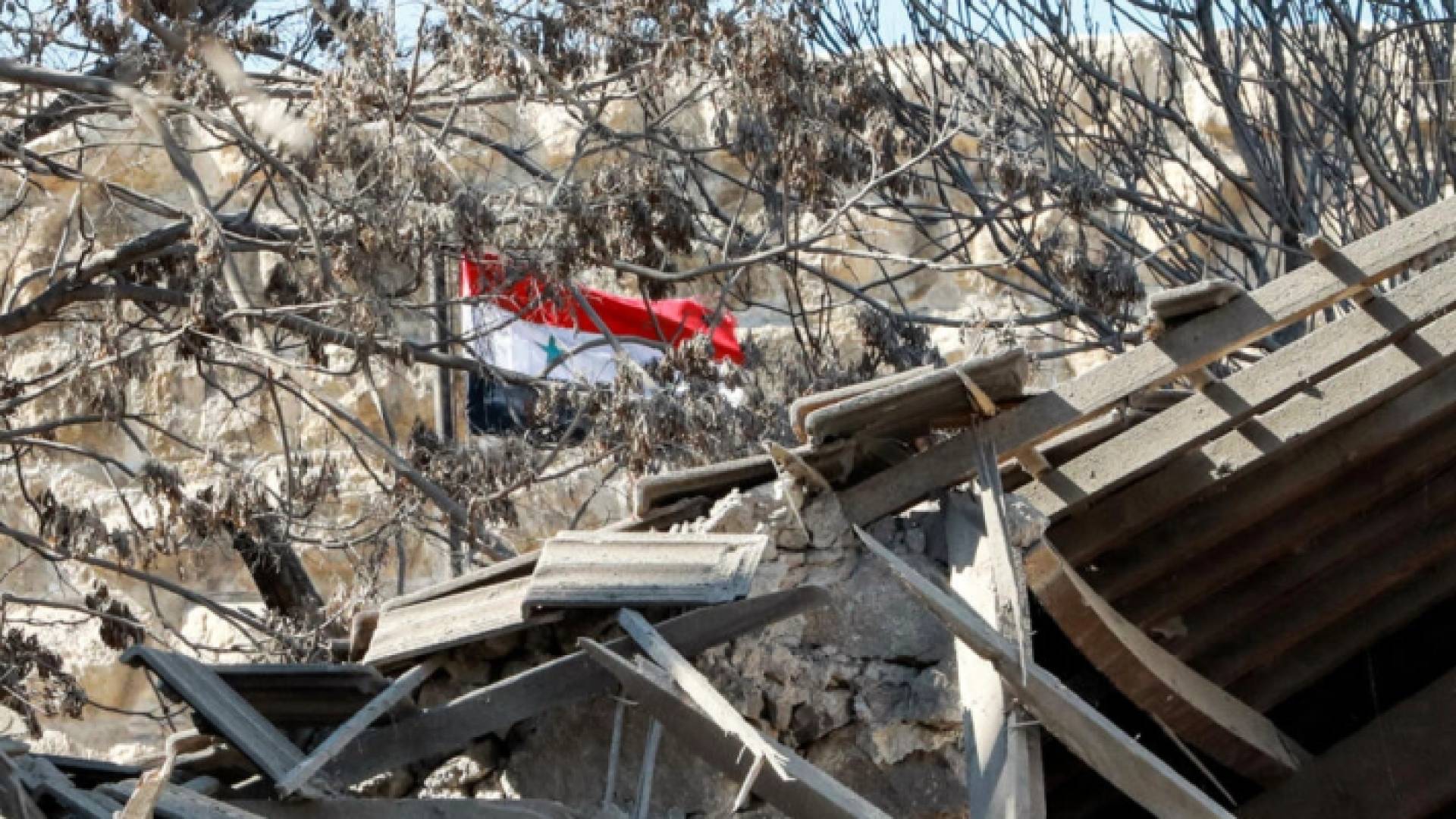 علم سوريا وسط ركام نتج عن غارة اسرائيلية